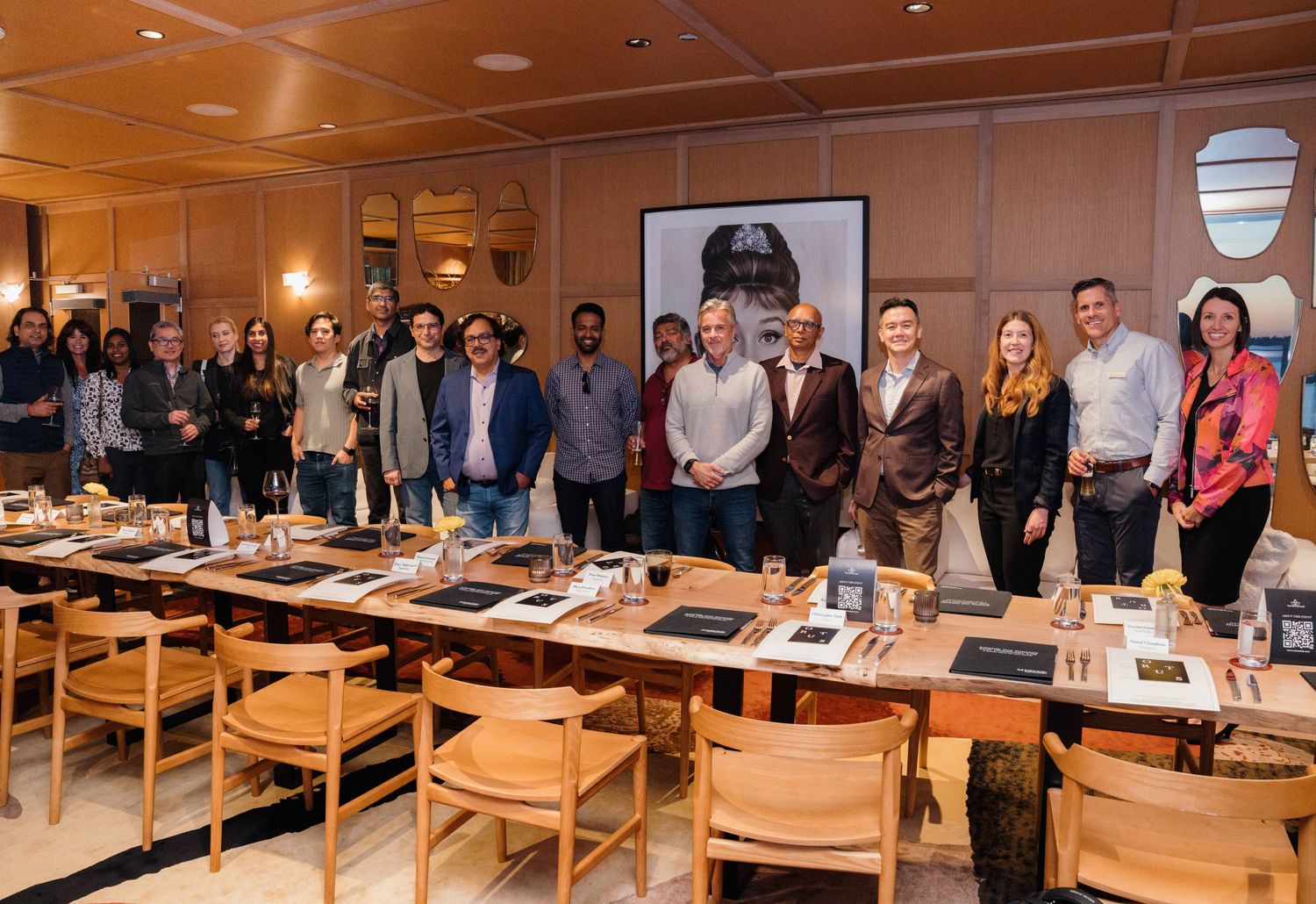 Business professionals gathered around wooden tables in a modern conference room during a corporate meeting.