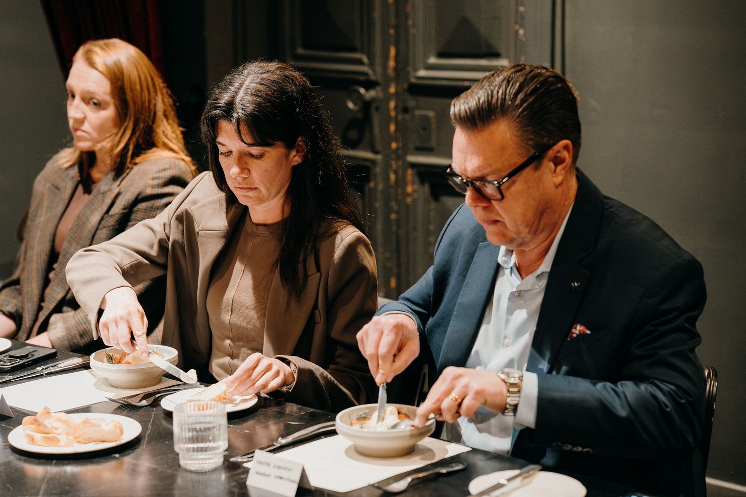 Business professionals seated at a restaurant table eating and working during a meeting.