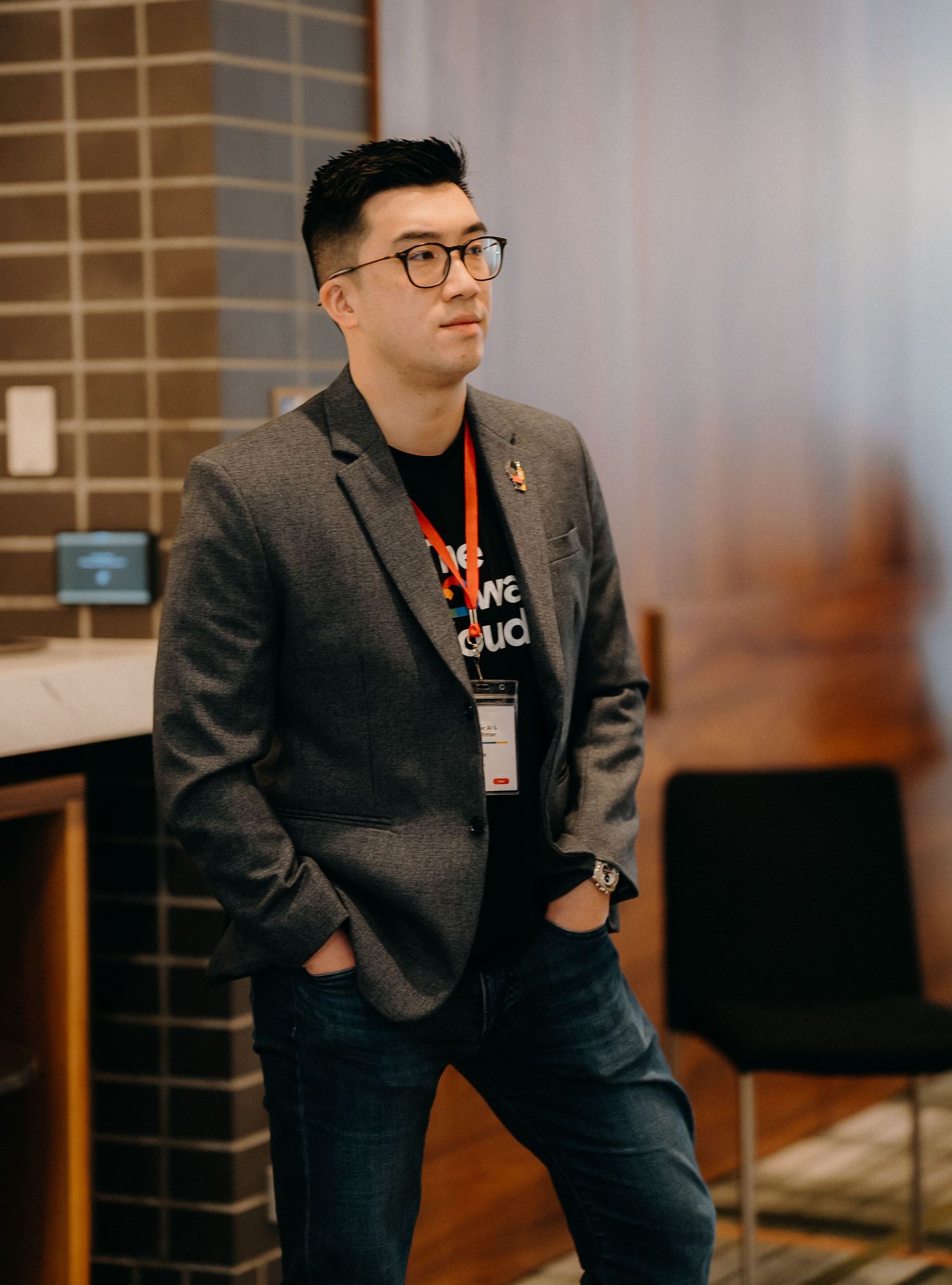 Professional in a dark blazer and glasses sits attentively during a business meeting or presentation.