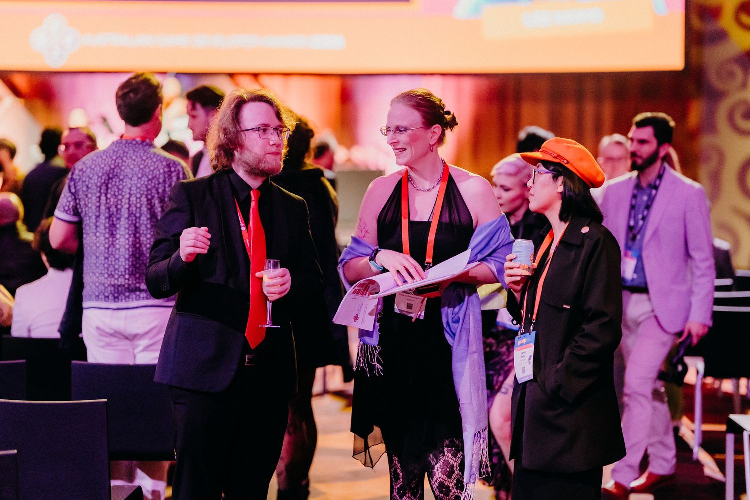 People socializing and networking at an evening event with warm lighting in an indoor venue.