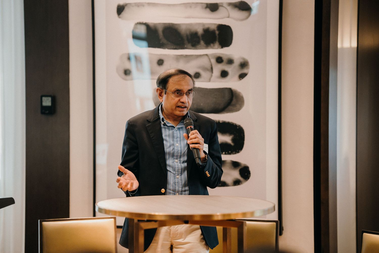 Business professionals collaborate during a meeting in a modern conference room with glass walls and black artwork.