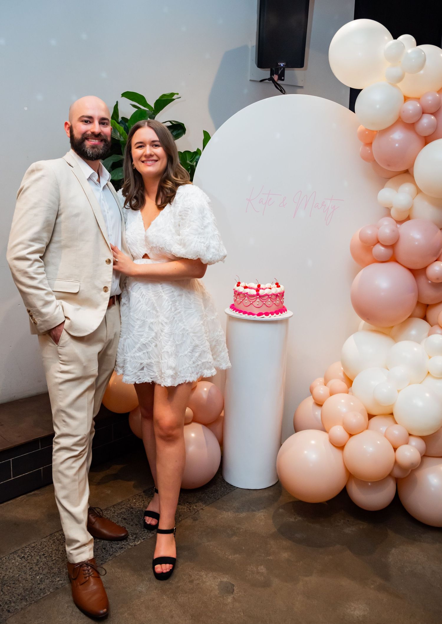 A series of photos showing a couple posing against a wall decorated with peach and white balloon garlands.