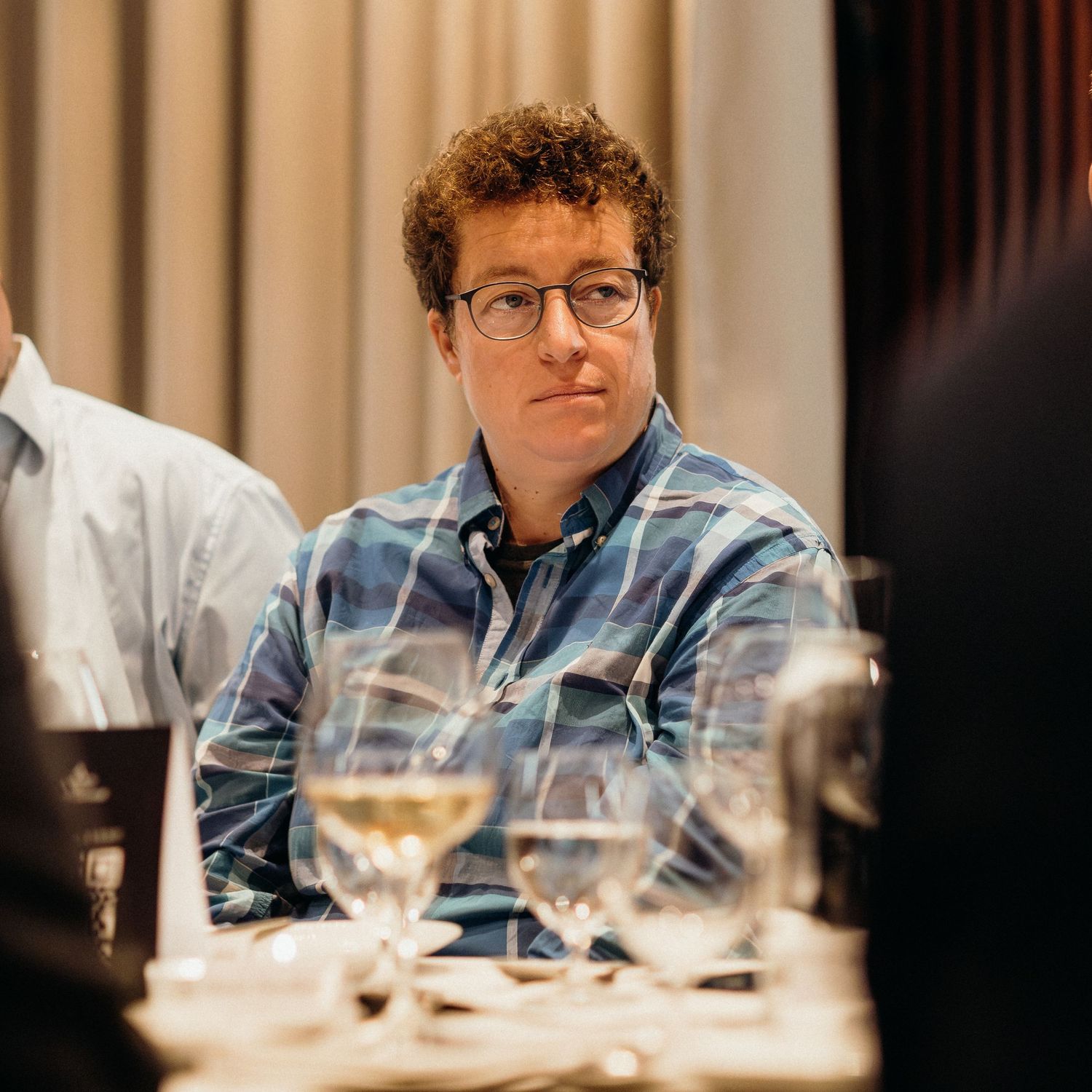 Wine tasting setup with multiple glasses on a wooden table during a professional tasting session.