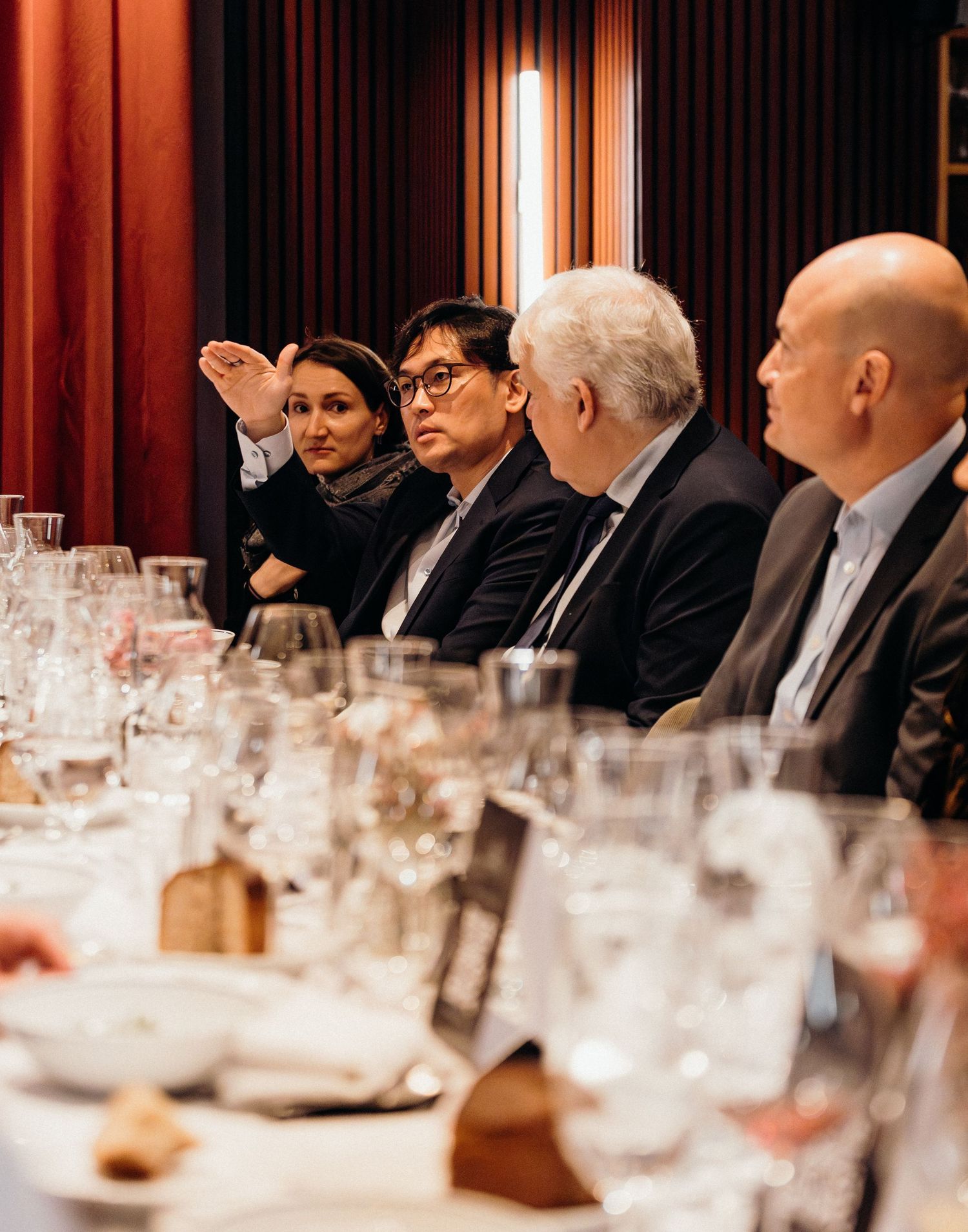 Business professionals seated at a formal dining table with glassware and place settings during an executive dinner event.