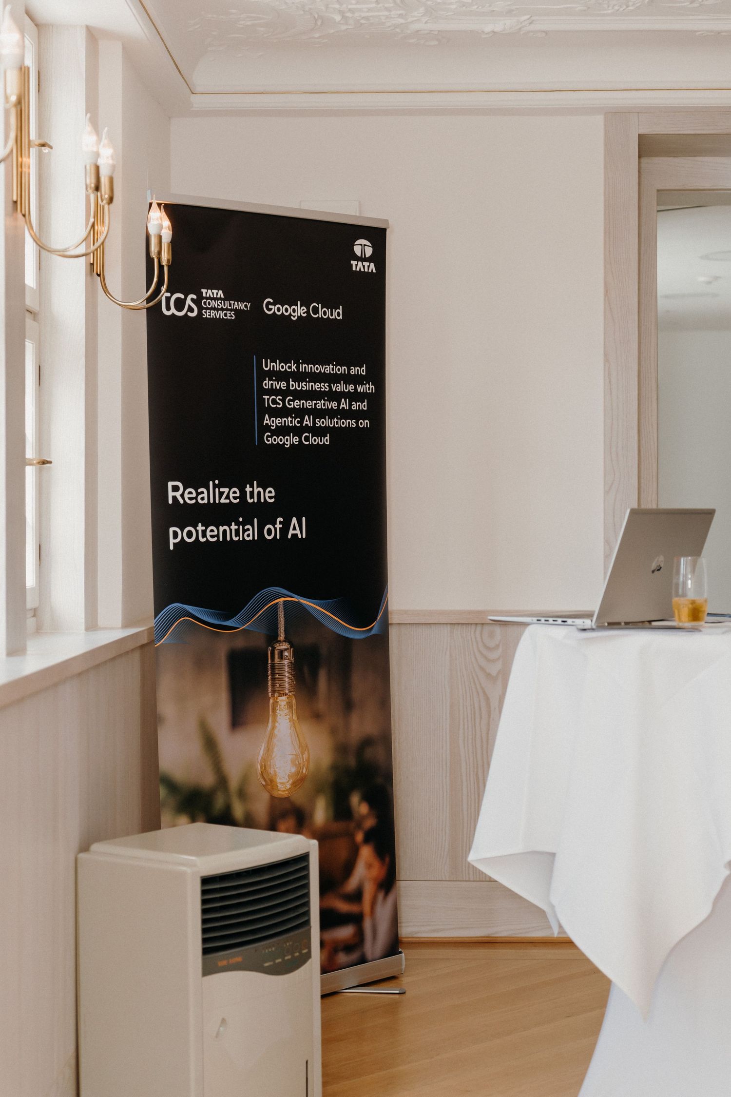TCS and Google Cloud AI solutions banner displayed at a corporate event venue with white tablecloth stand.