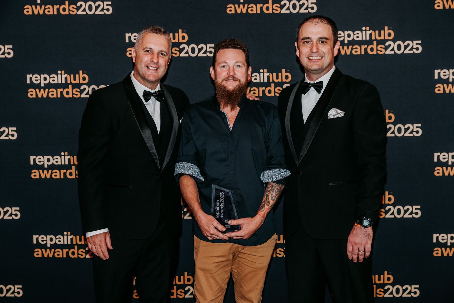 A group of people in formal attire pose together at the Repair Hub Awards 2025 event against a branded backdrop.