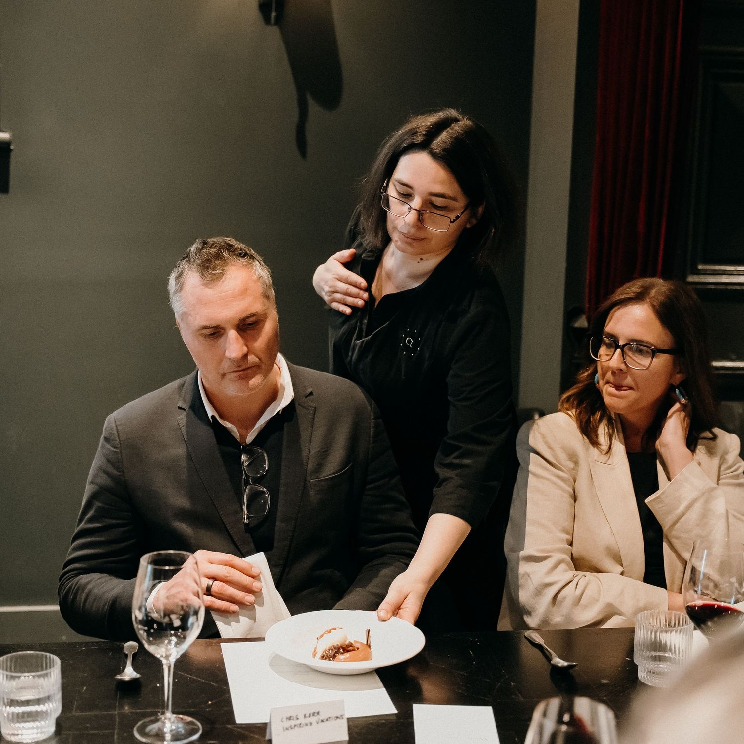 Business professionals gathered around a long table for a formal dinner meeting in a dimly lit restaurant setting.