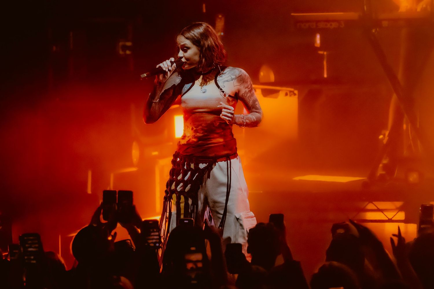 Concert performers on stage bathed in dramatic red lighting create an energetic atmosphere during a live music performance.