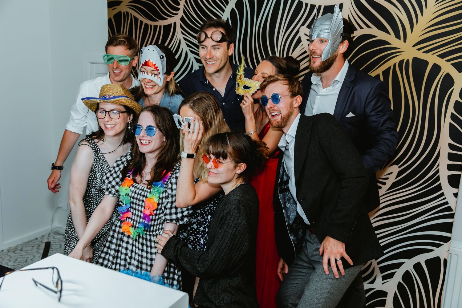 Group of party guests pose together in front of zebra print backdrop at a photo booth event.