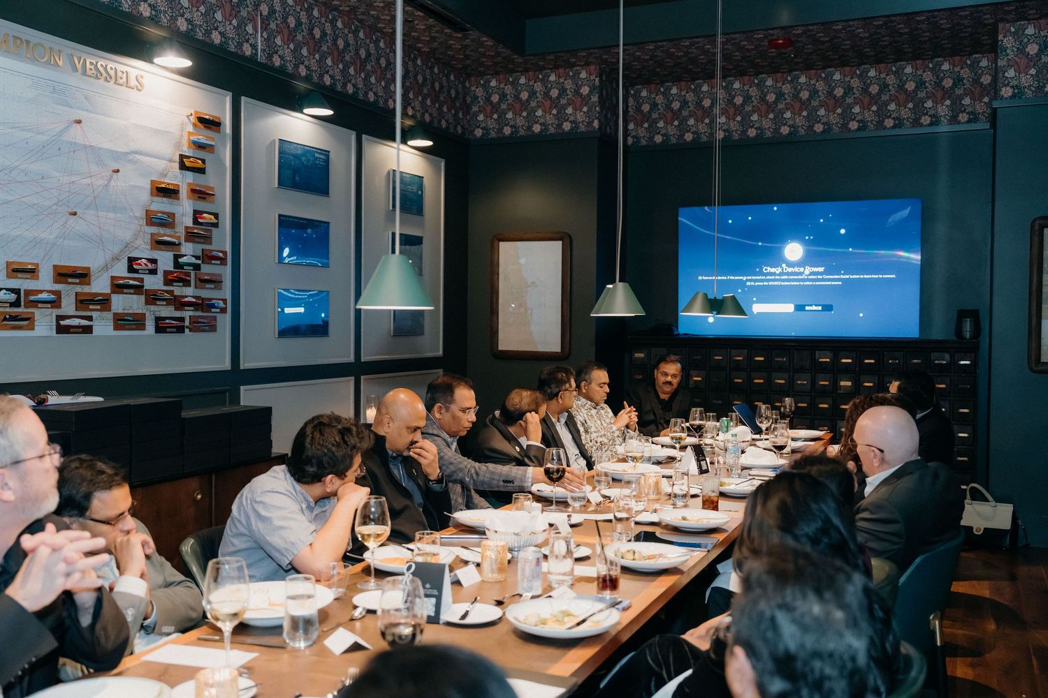 Business professionals gathered around tables in a modern conference room for a corporate meeting and presentation.