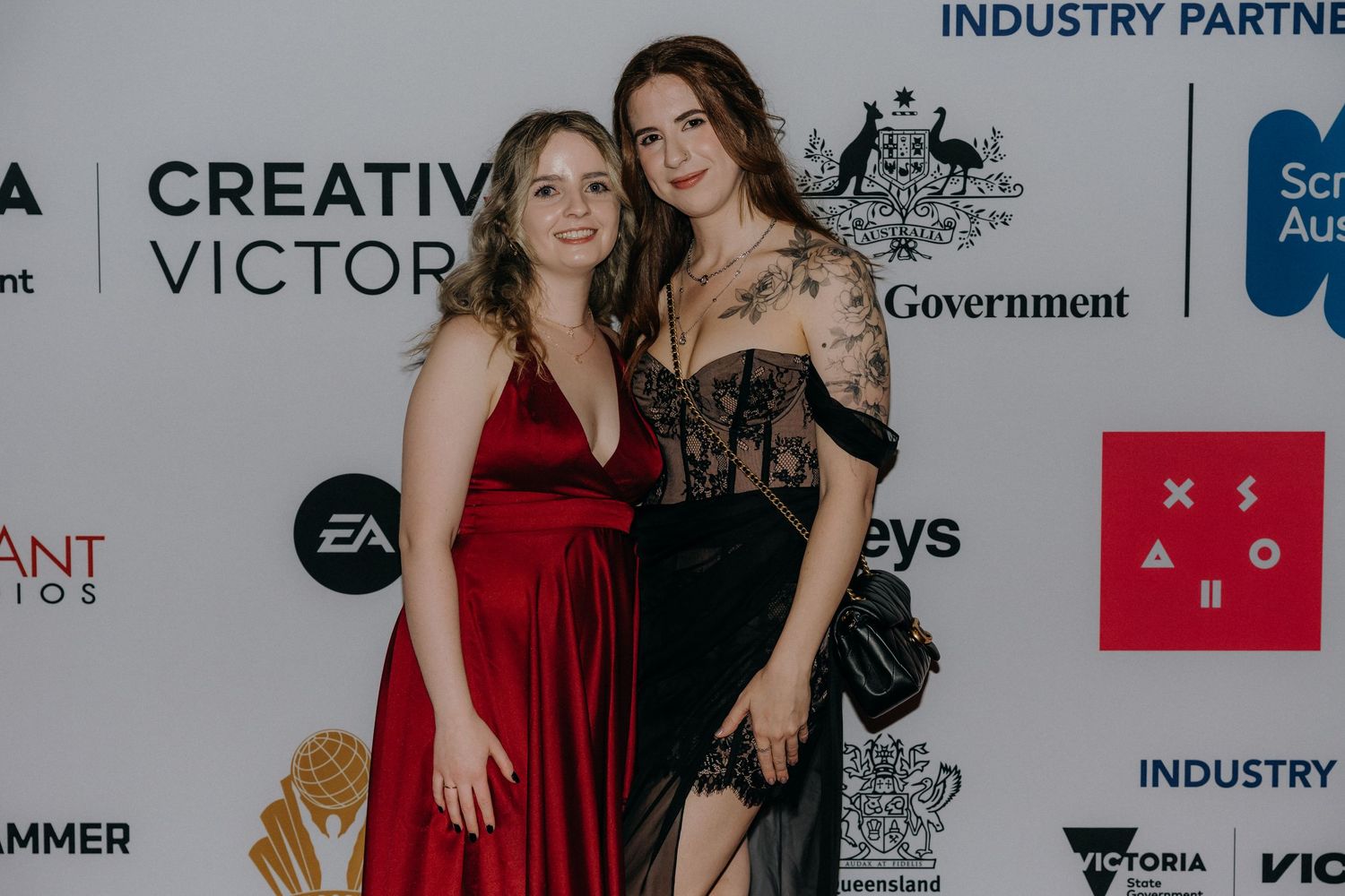 People posing together at an industry event with corporate sponsor logos visible on the backdrop wall.