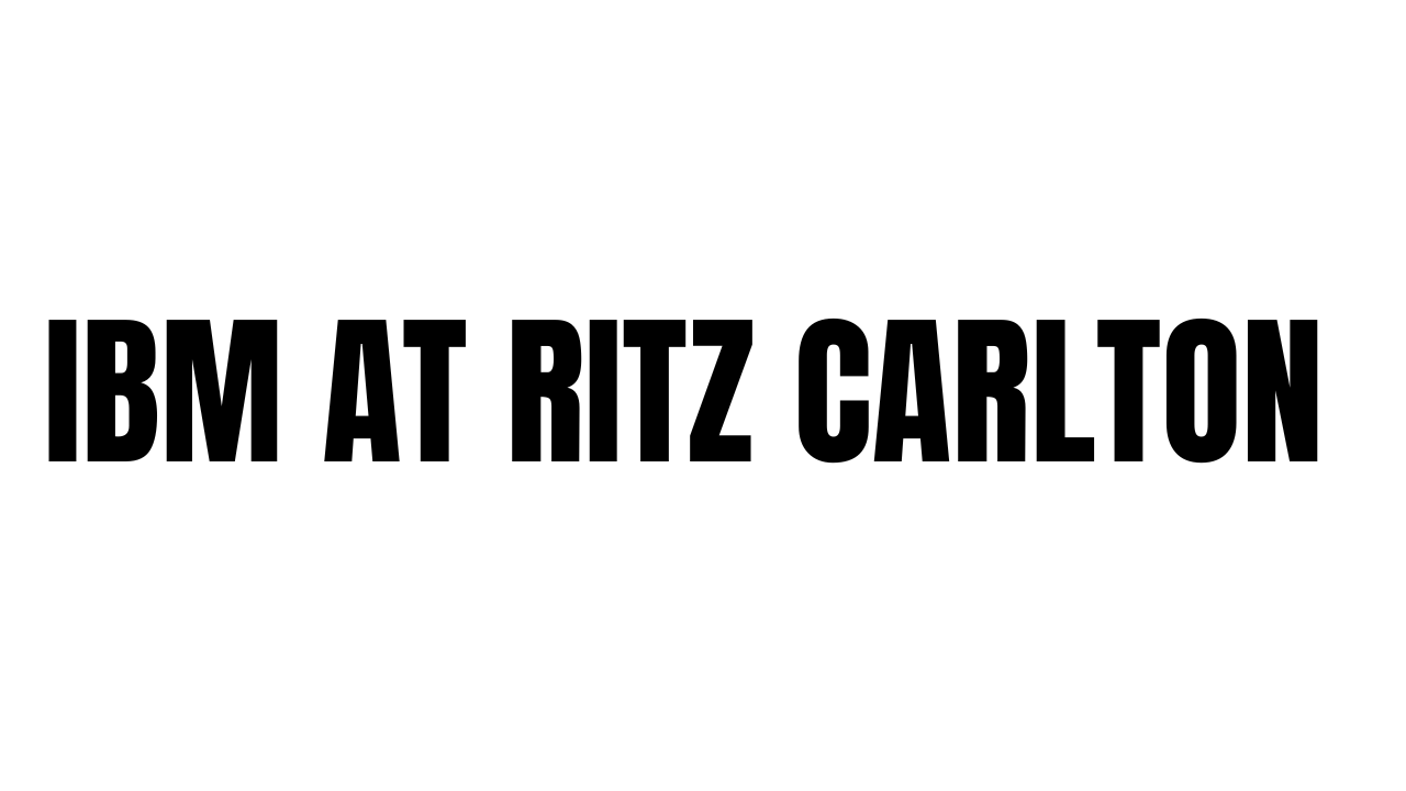 A sleek black IBM logo displayed prominently on a Ritz Carlton hotel building exterior.