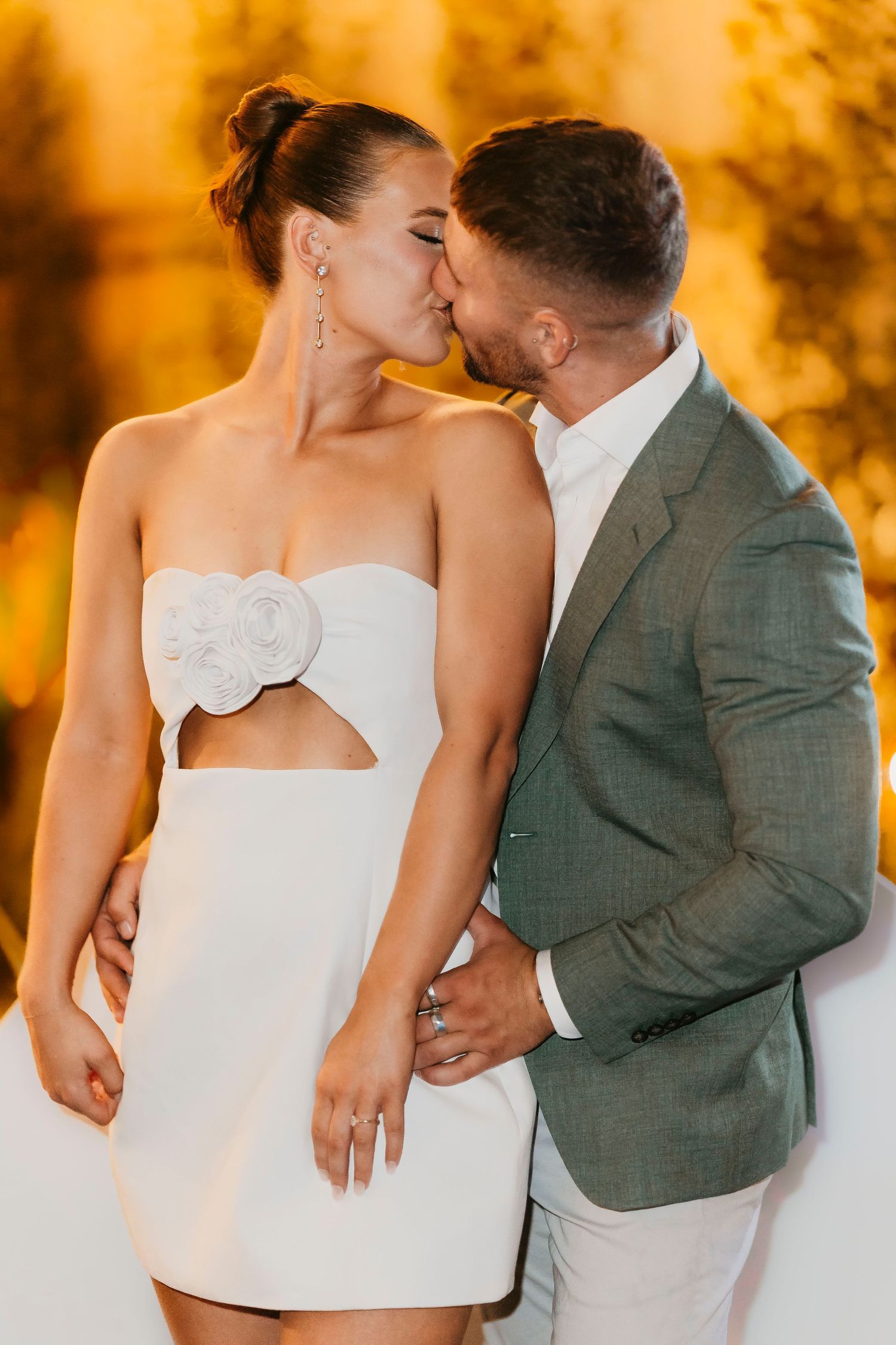 A romantic couple in wedding attire share tender moments against a golden autumn backdrop.