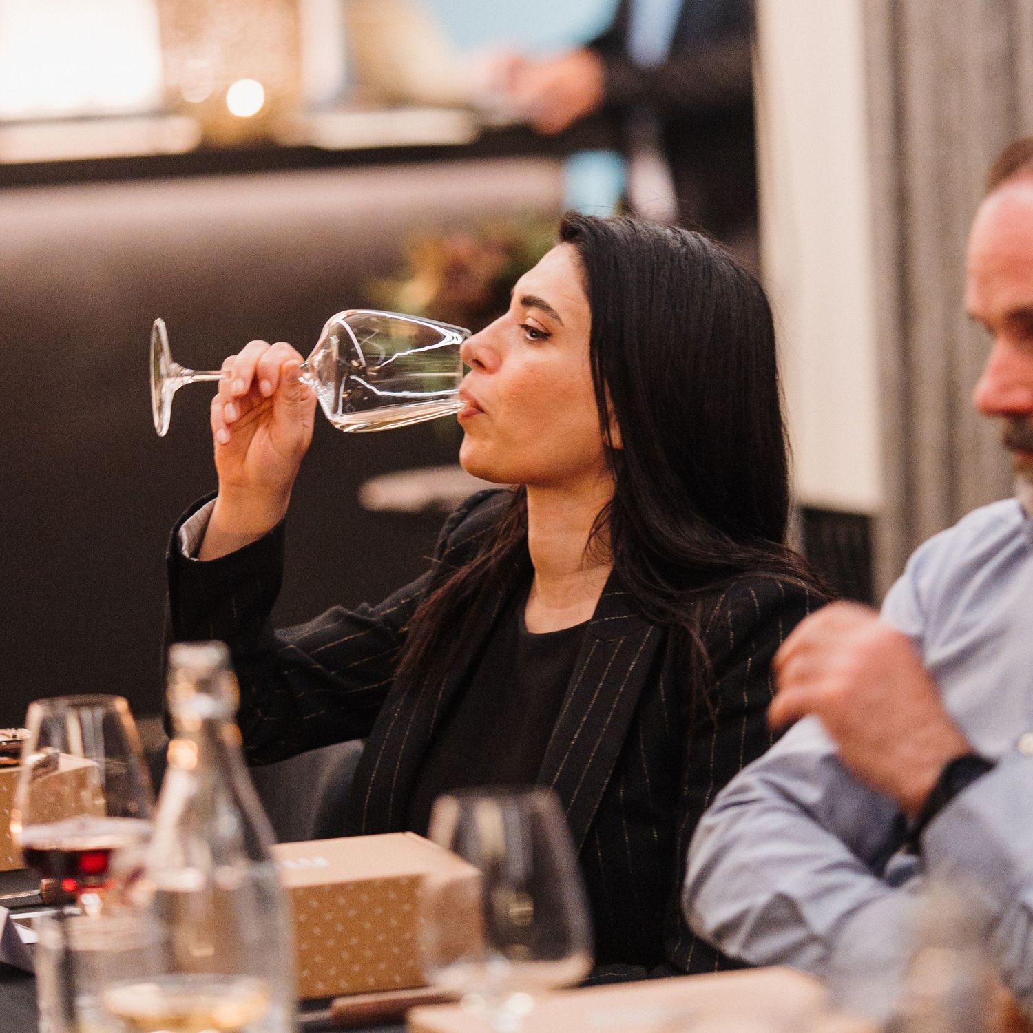 Person enjoying a glass of red wine at a restaurant table during a dining experience.