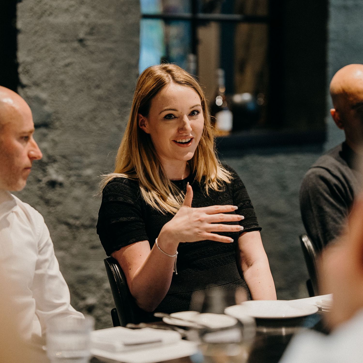 Group of people engaged in animated conversation during a social gathering at a restaurant.