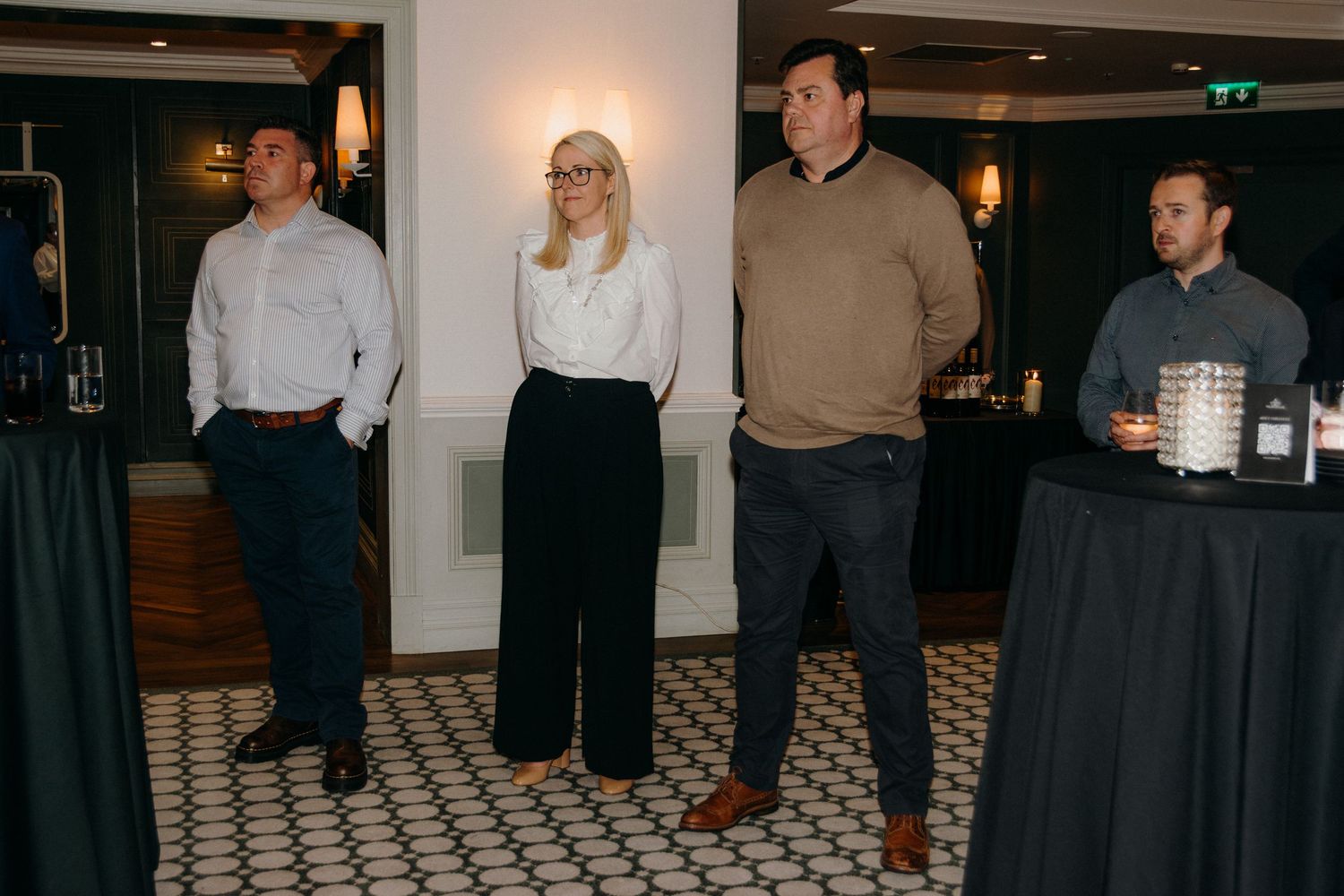 A group of people gathered in a dimly lit restaurant or bar with tiled floors and warm lighting.