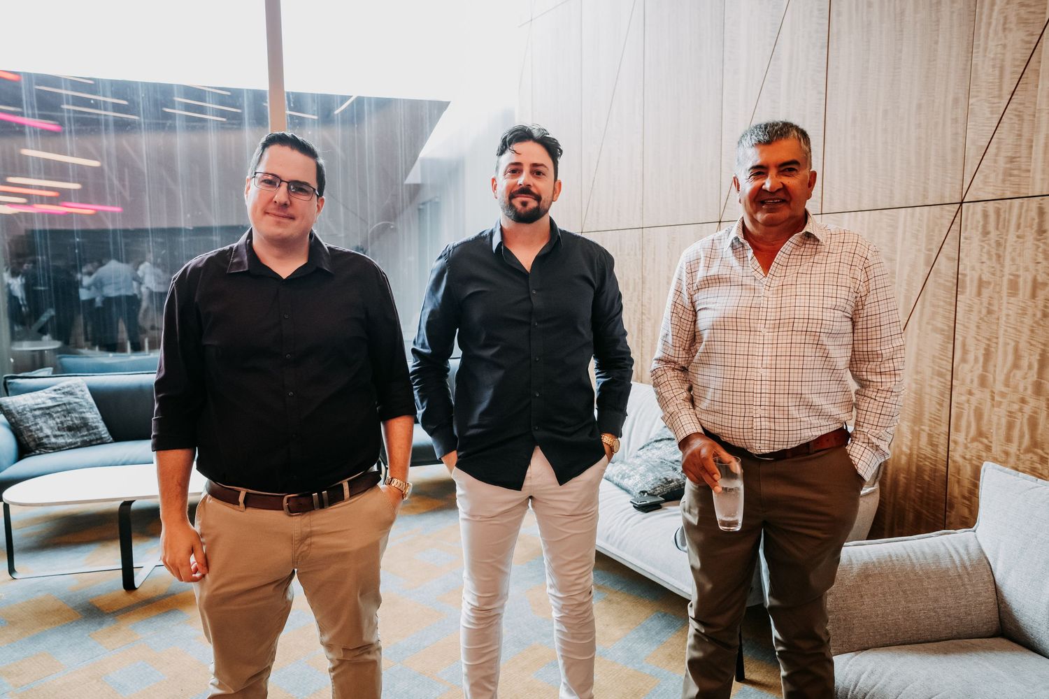A group of people standing together in an office hallway wearing business casual attire.