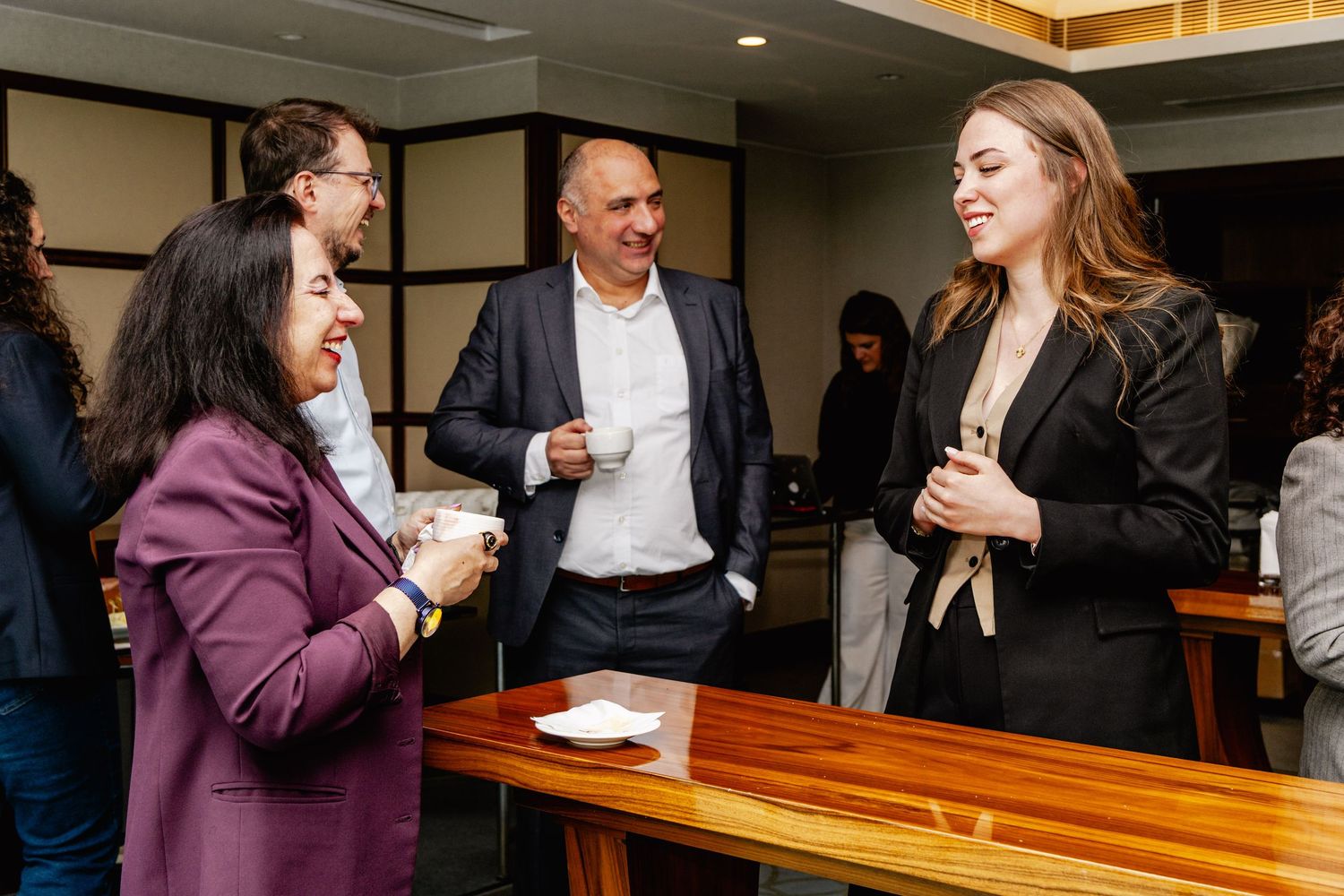 Professionals networking at a business event, engaged in conversation over coffee in a modern conference venue.