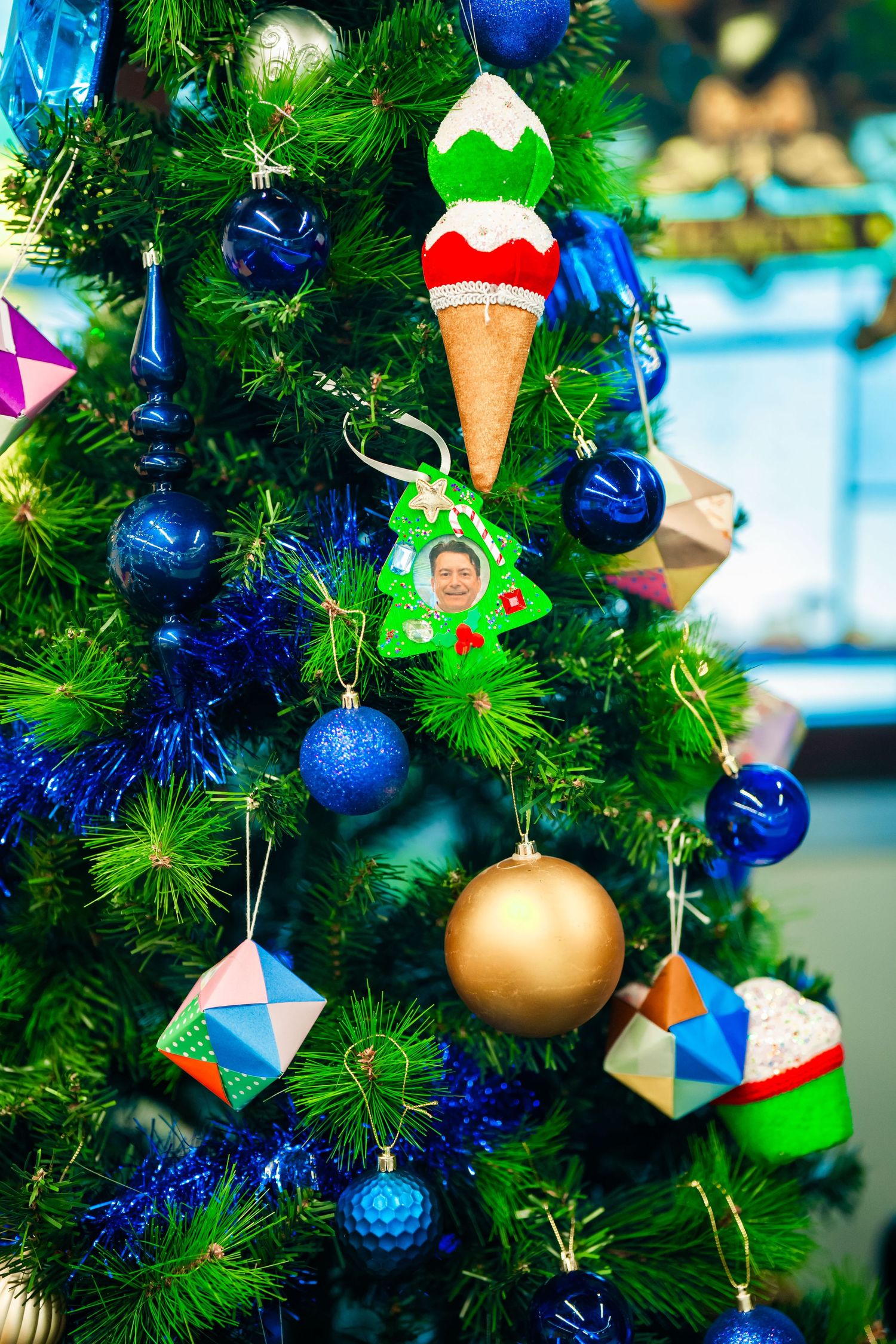 Close-up view of Christmas tree decorated with blue ornaments, gold baubles and ice cream cone decorations.