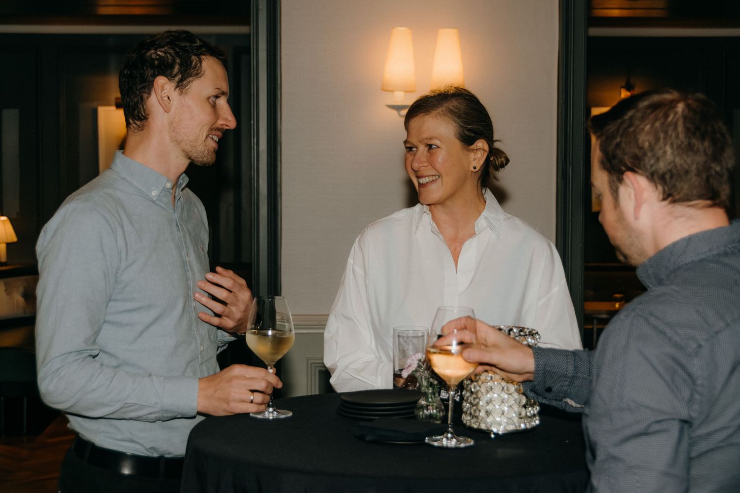 A series of candid photos showing people engaged in conversation at what appears to be an evening social gathering.