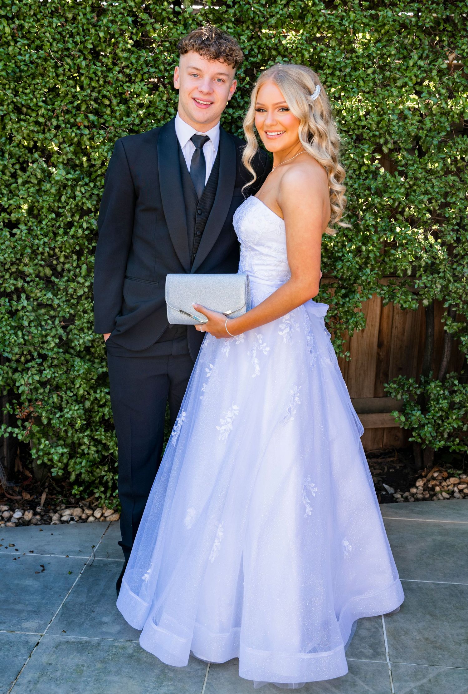 Couple in wedding attire sharing romantic moments against a green hedge backdrop in a series of outdoor photos.
