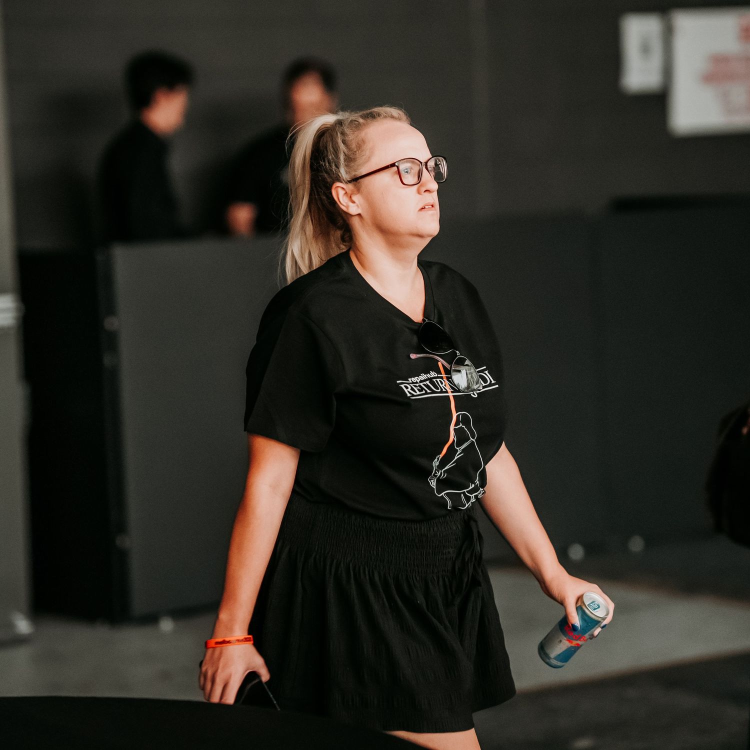 Person in black clothing performs dance movements in a dimly lit studio space.