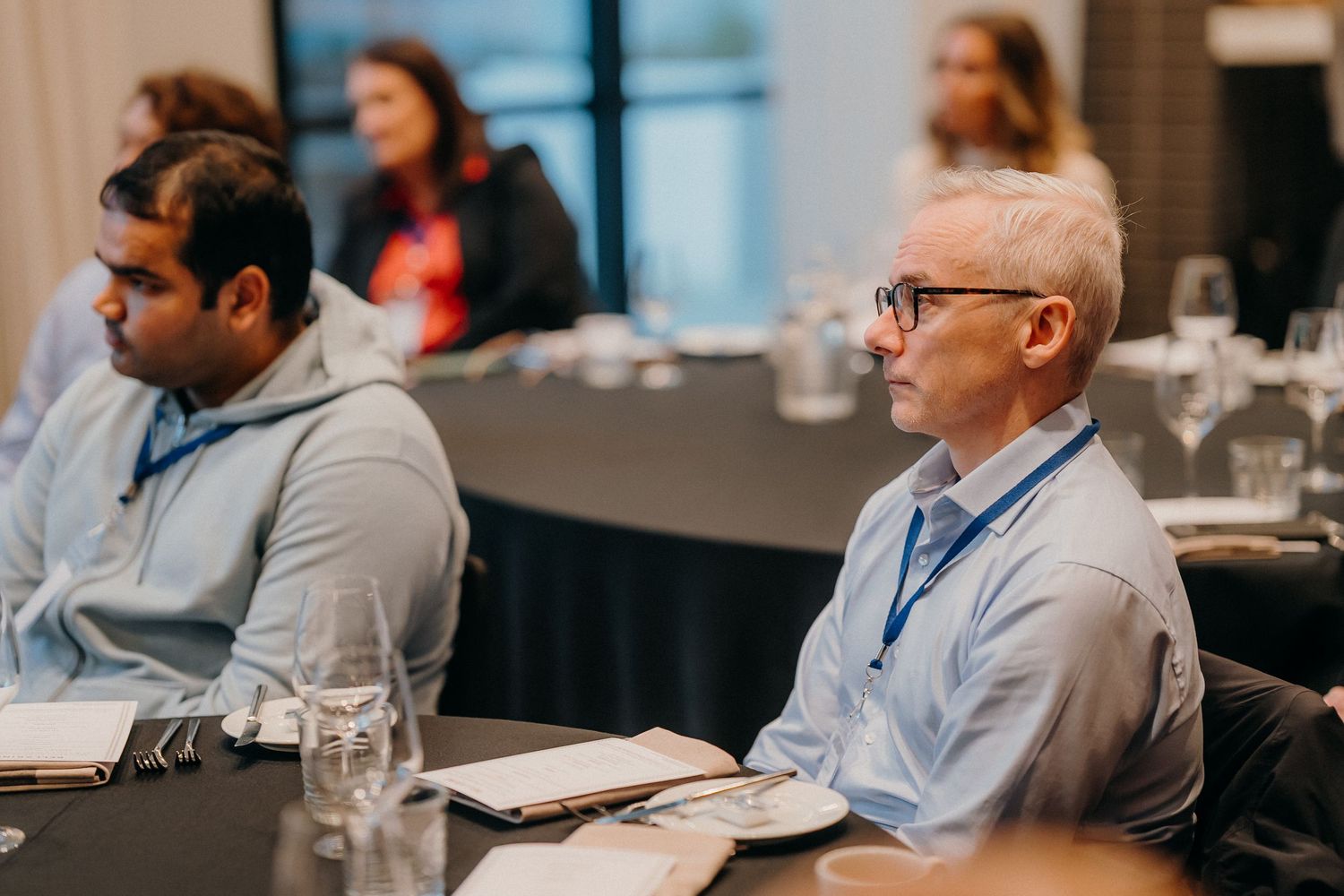 Attendees listen attentively during a professional business conference in a modern meeting room setting.