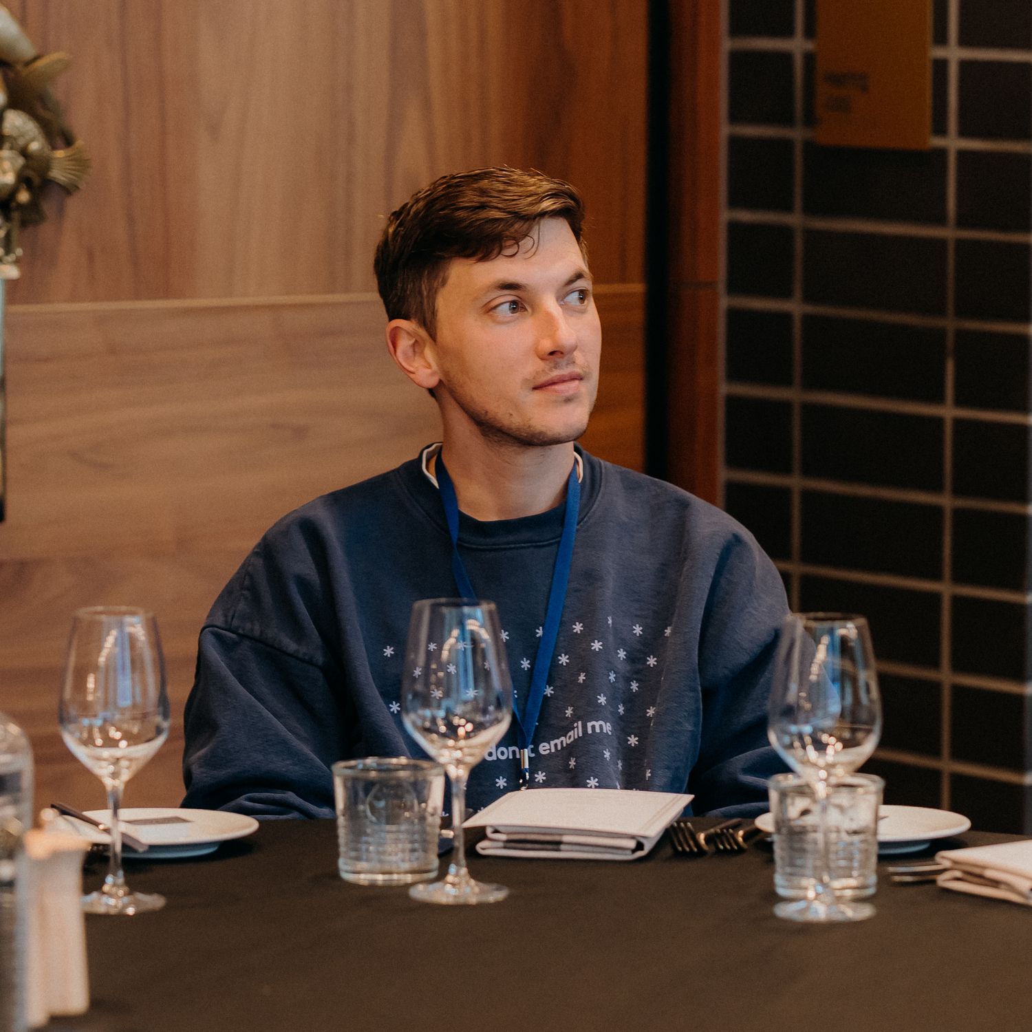 Someone in a navy blazer sits at an elegant restaurant table with wine glasses and place settings arranged neatly.