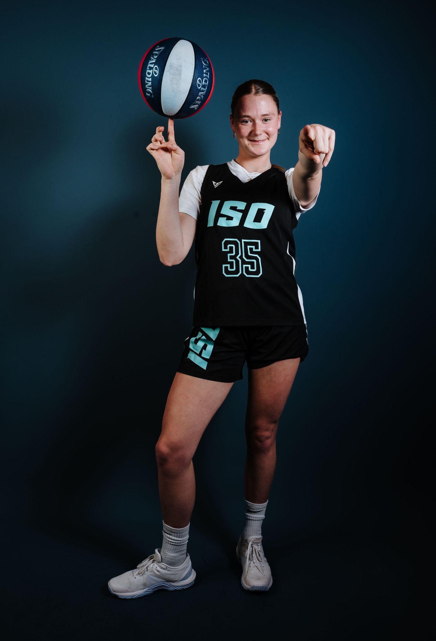 Basketball player in black ISO jersey number 35 poses with ball against dark background in studio setting.