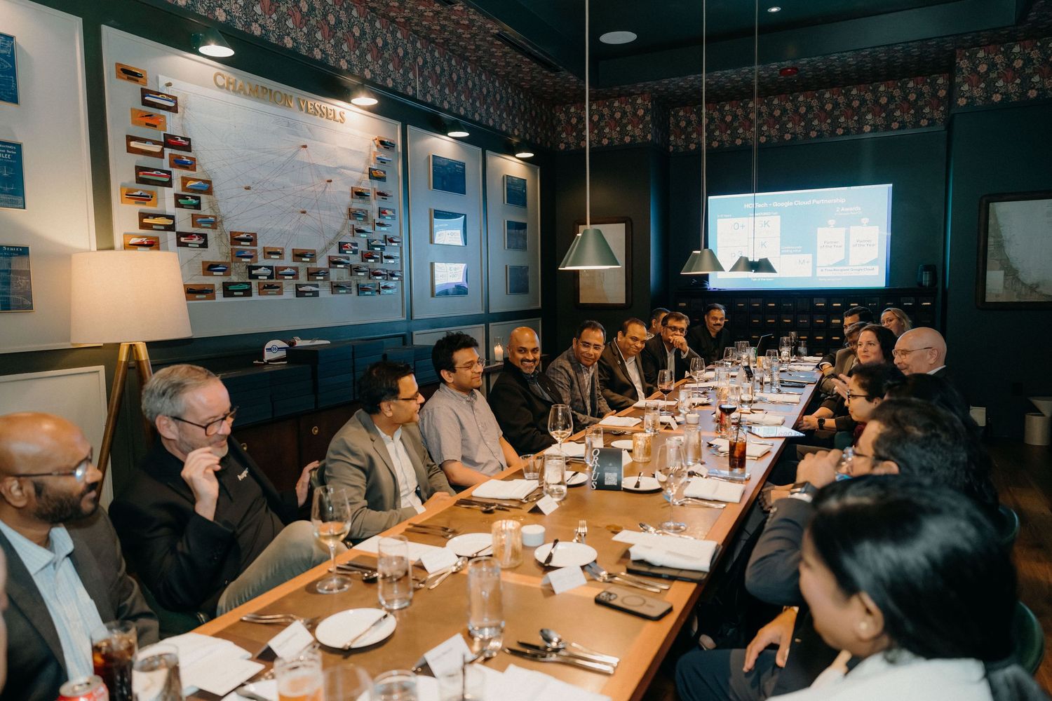 Business professionals gathered around tables during a corporate dining event in a modern restaurant setting.