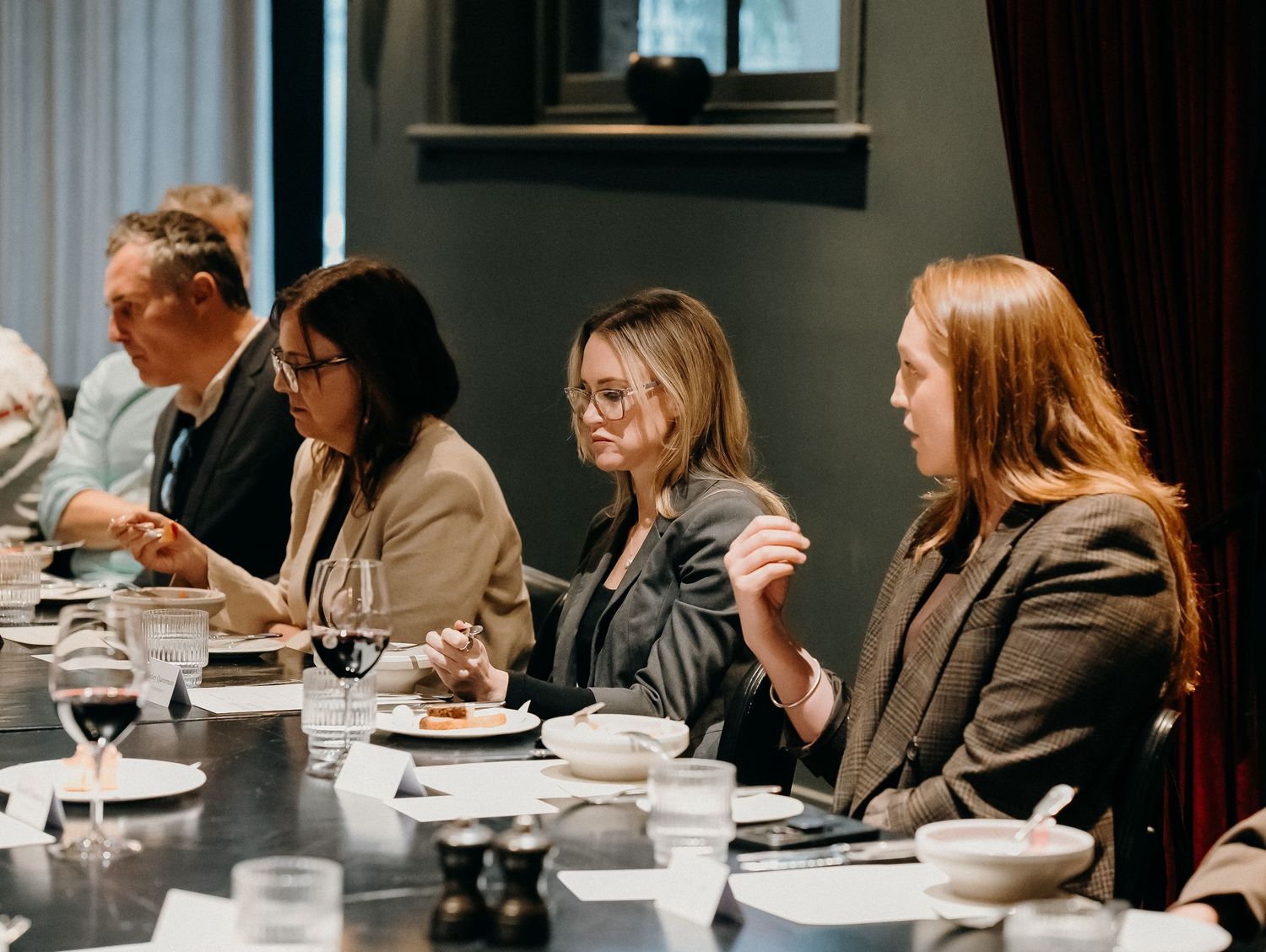 Business professionals dining together at a formal restaurant meeting with water glasses and place settings on the table.