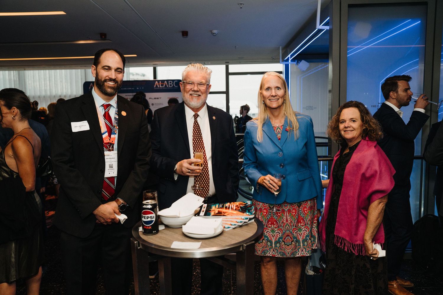 Business networking event at evening reception with people mingling and conversing in formal attire.