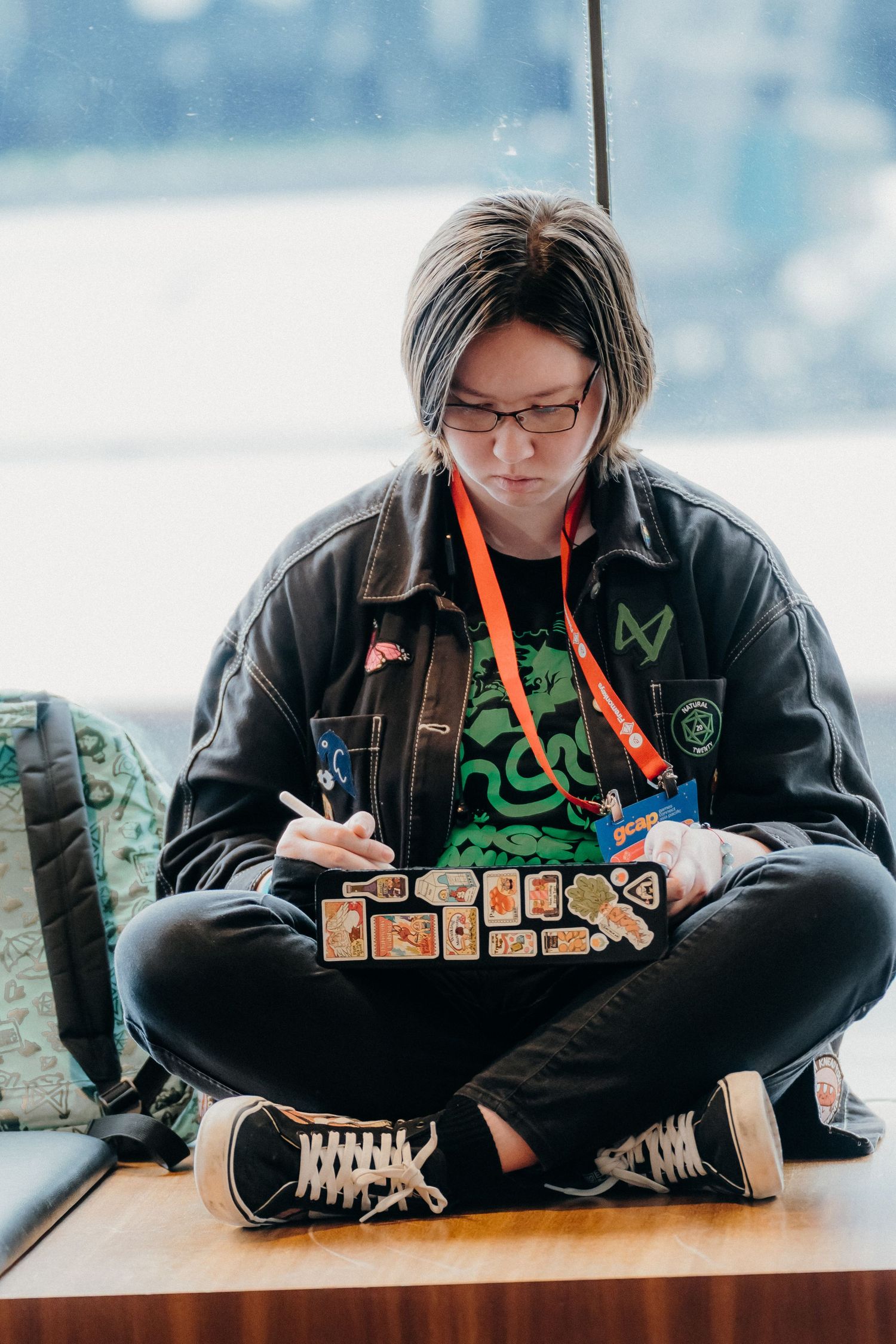 Student in black hoodie studying at desk with colorful stationery and supplies spread out in front of them.