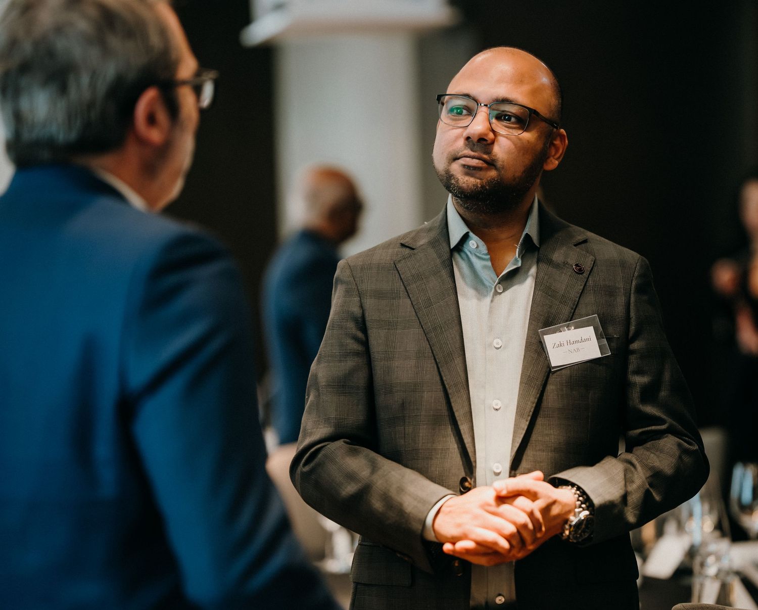 Professional speakers engage in animated discussion during business conference presentation.