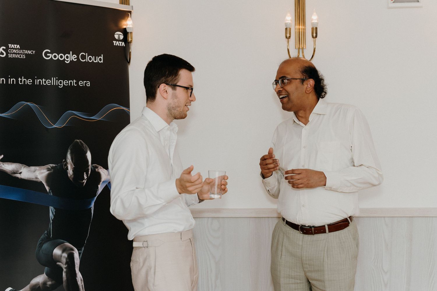 Two professionals networking at a Google Cloud and Tata Consultancy Services event, engaged in conversation.