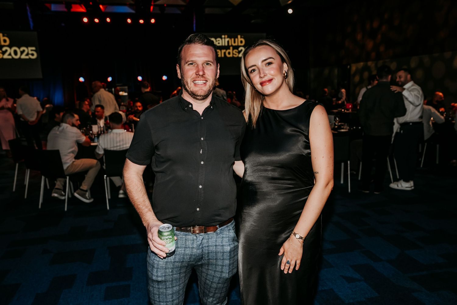 People stand in a dimly lit venue during what appears to be a social gathering or event.