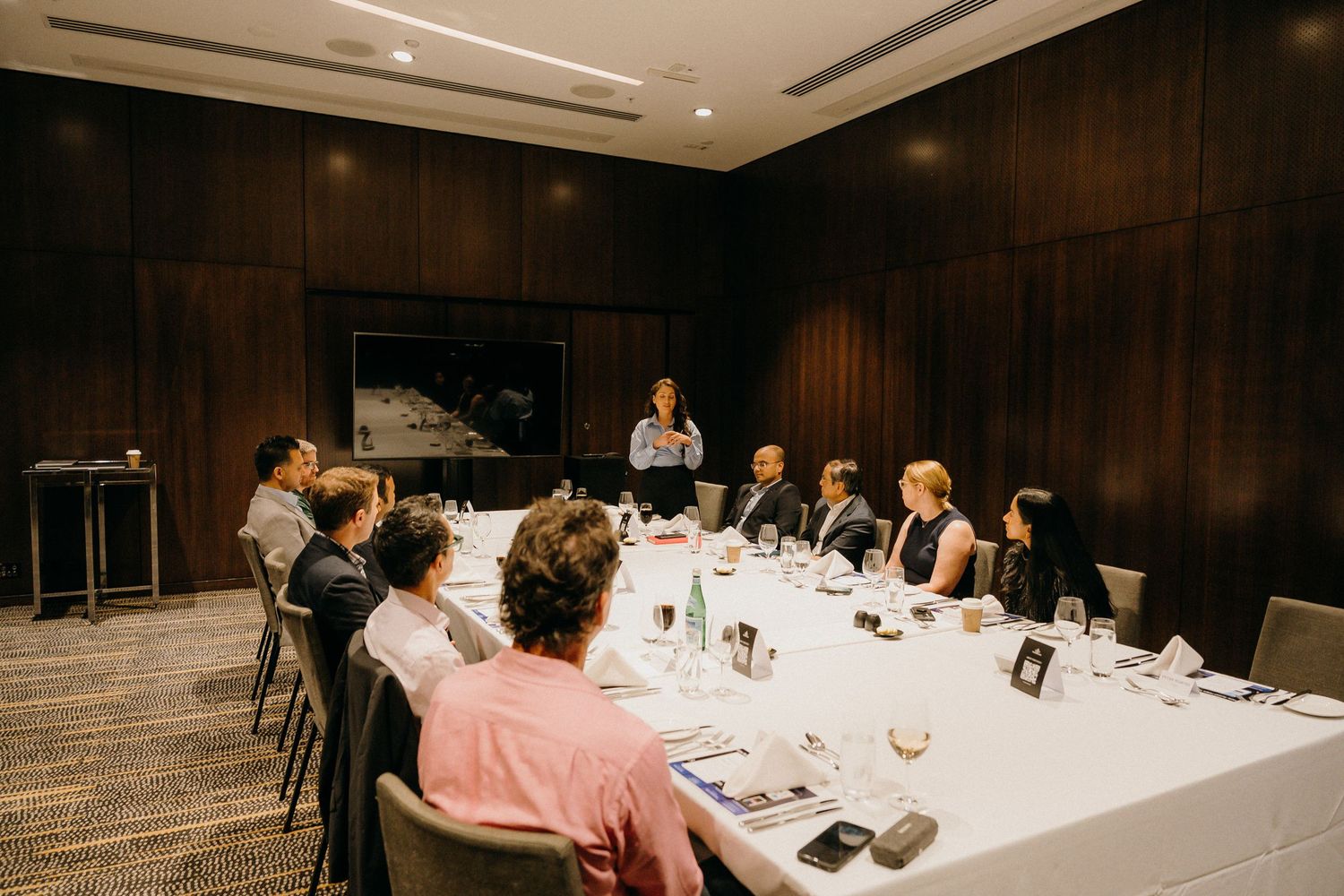 Professional business meeting with colleagues gathered around a formal dining table in an elegant conference room.