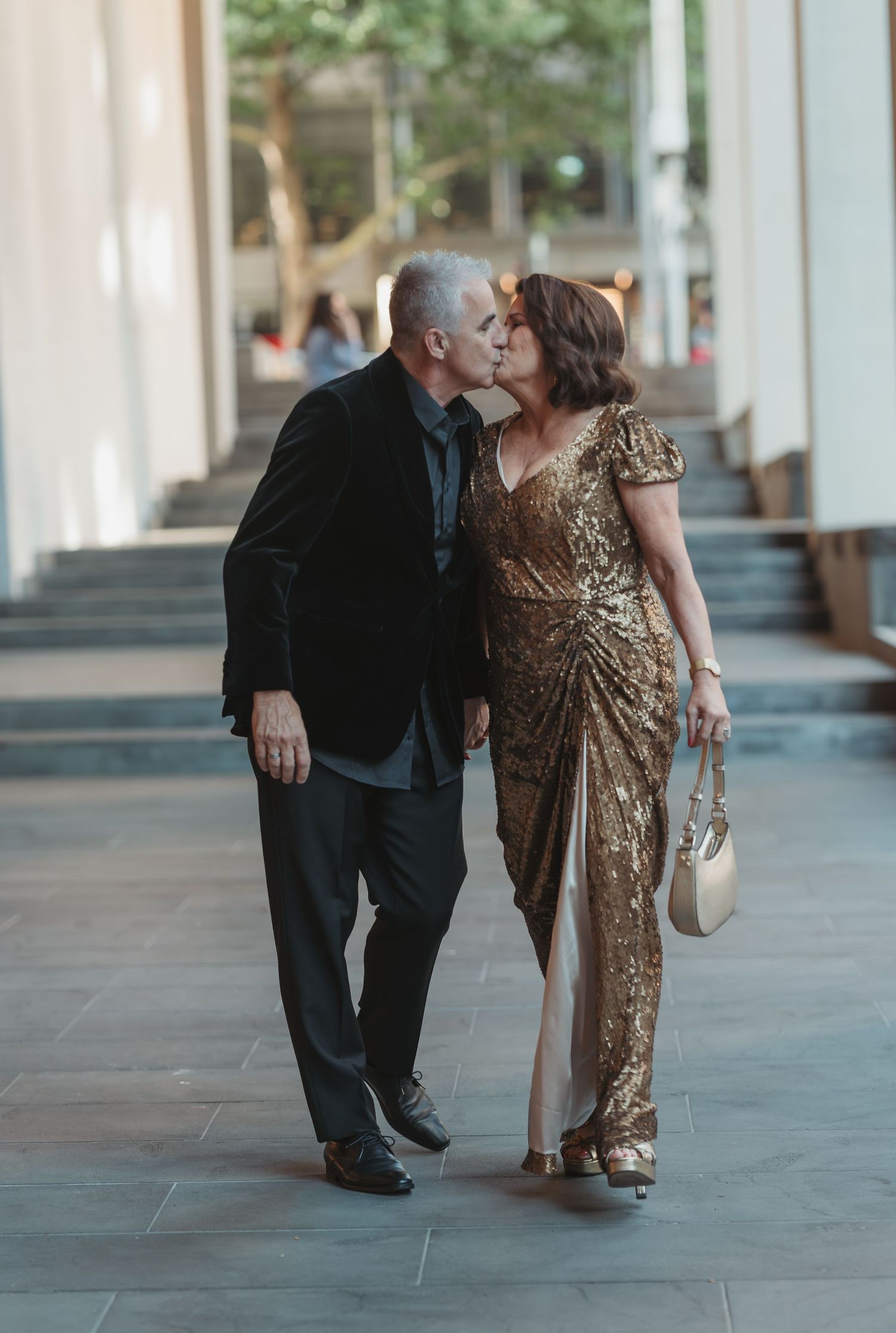 A couple in formal attire share a romantic moment in a series of photos along an elegant corridor.