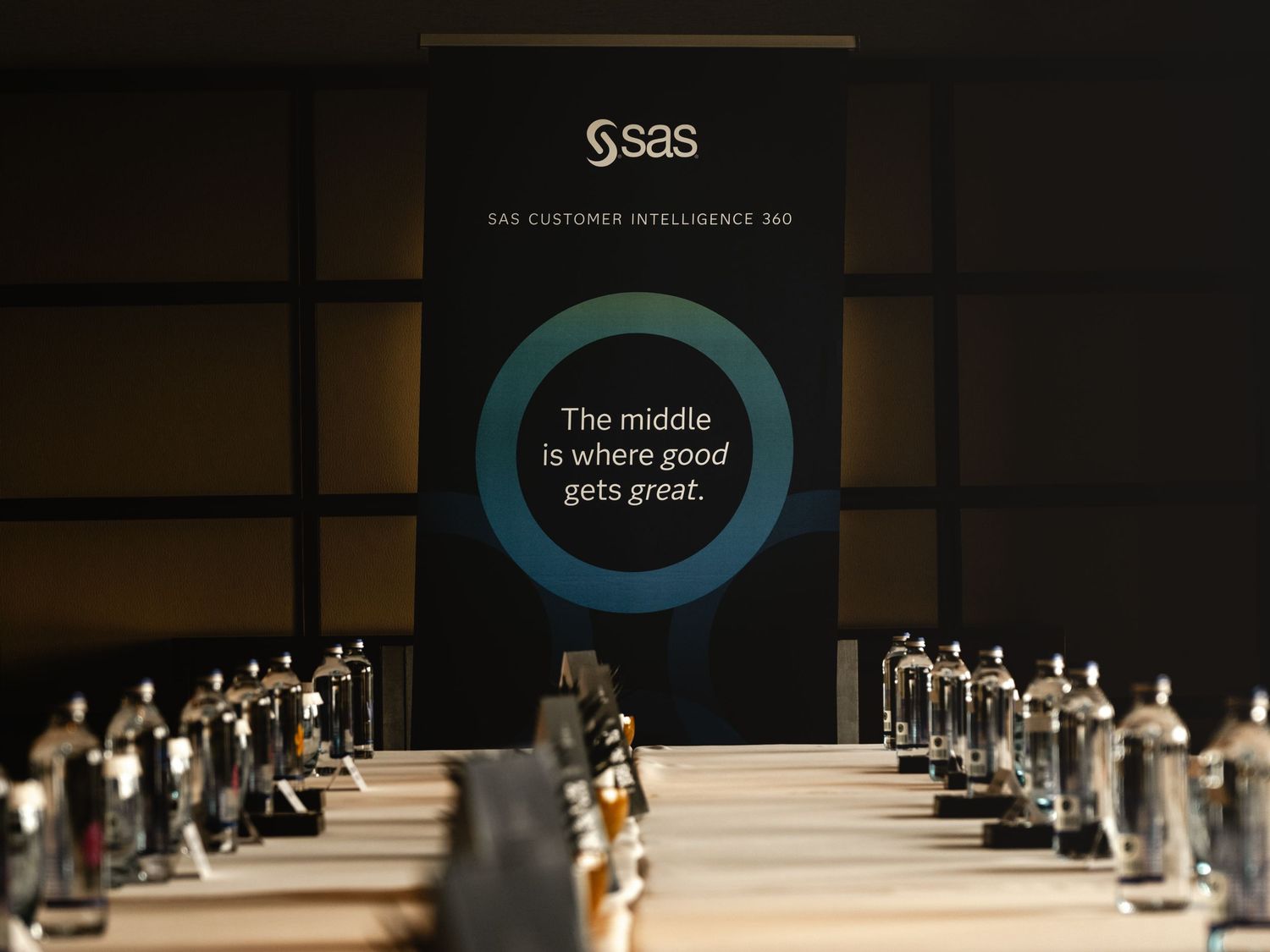 SAS Customer Intelligence 360 banner display reading 'The middle is where good gets great' at a conference event.