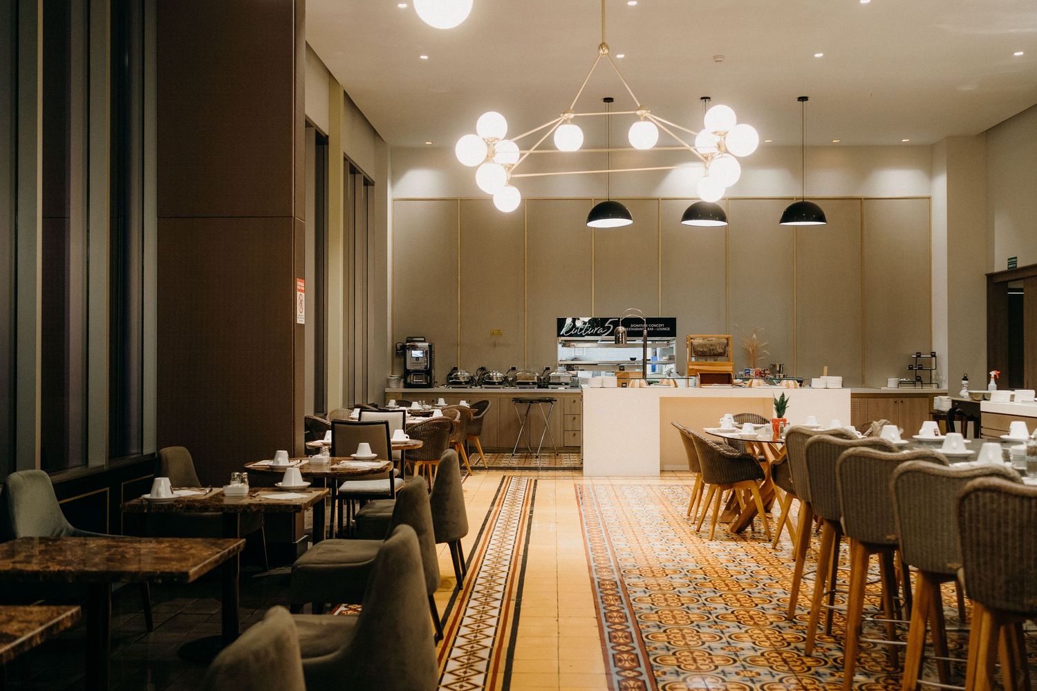 Modern restaurant interior with wooden tables and chairs illuminated by pendant lights in a minimalist dining space.