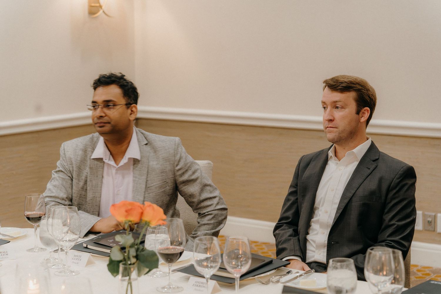Business professionals seated at a dining table engage in conversation during a formal meeting.