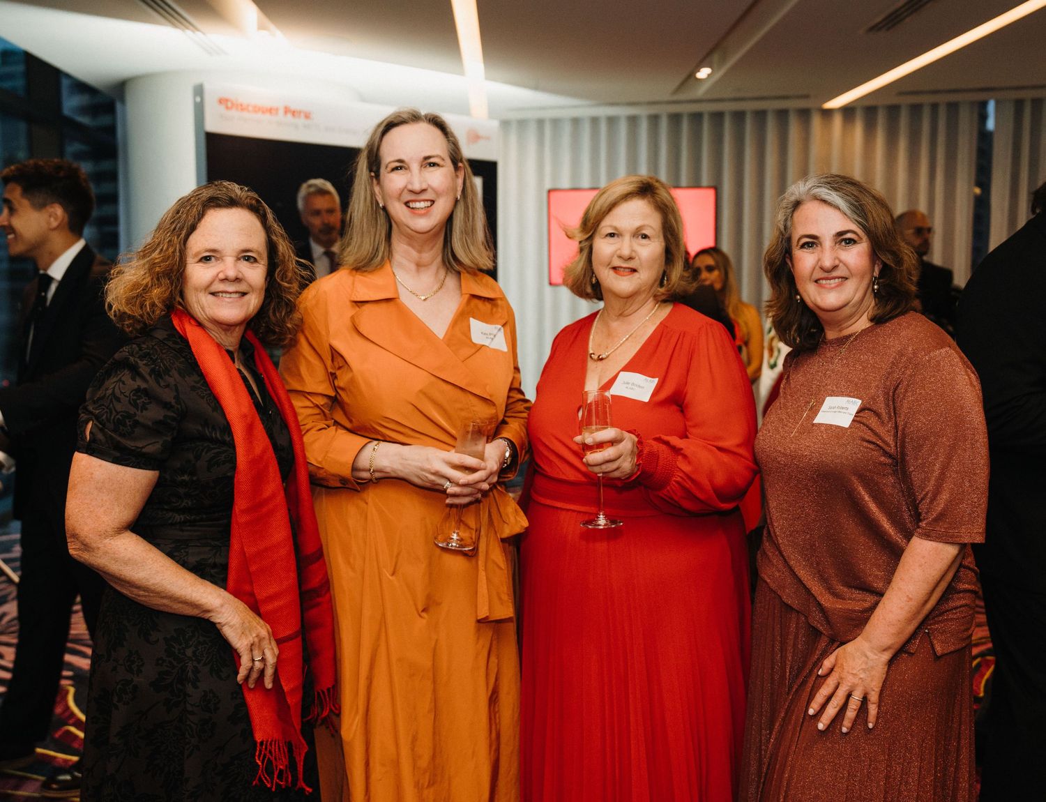 A group of people wearing red and orange outfits gather together at a social event.
