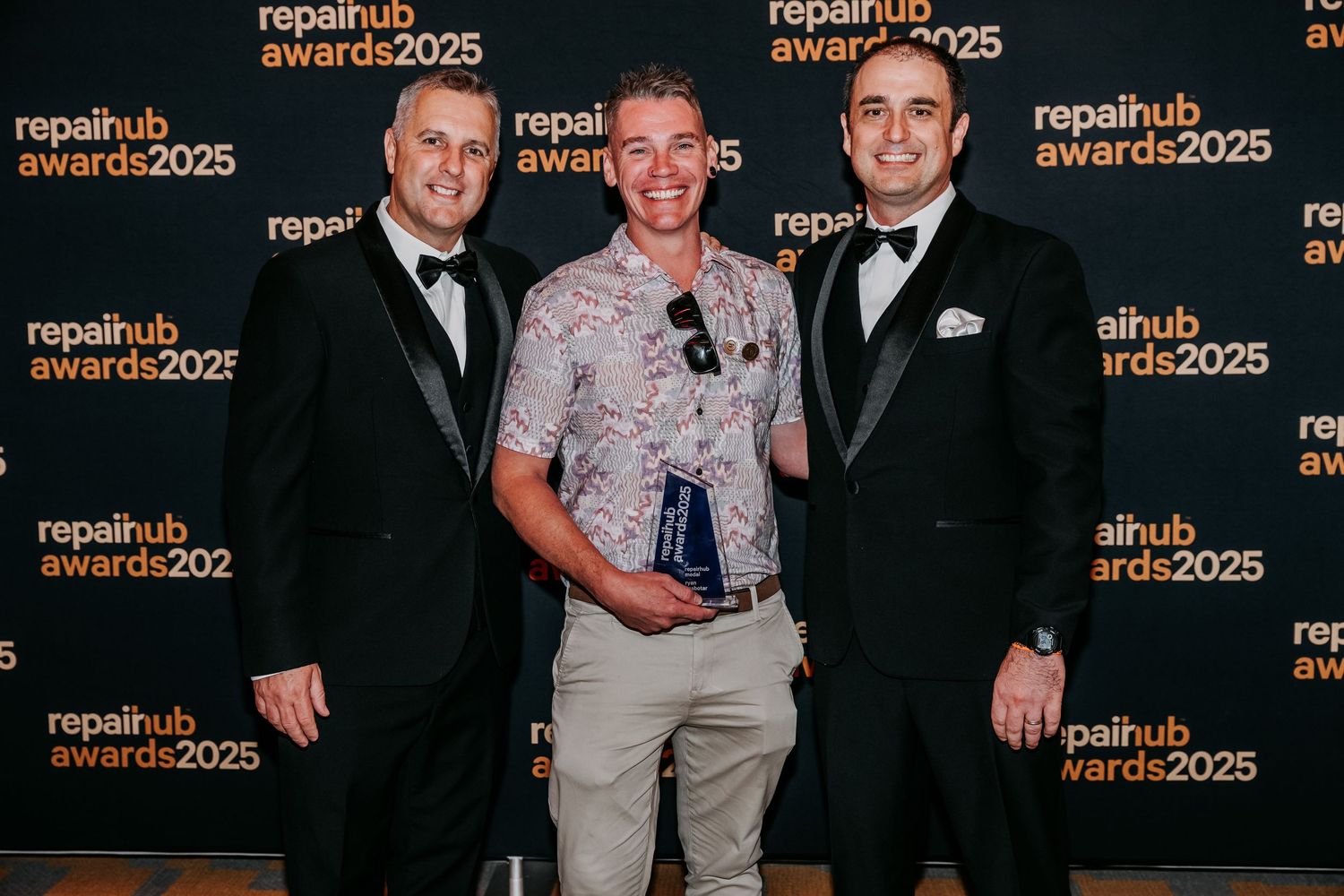 Attendees pose with awards at the RepelHub Awards 2025 event against a branded step-and-repeat backdrop.