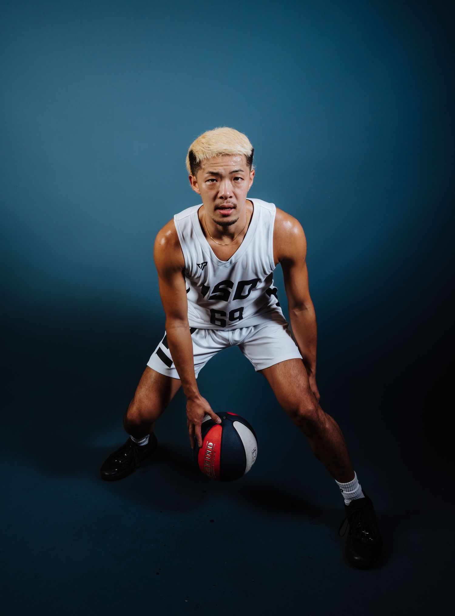 Basketball player in white jersey crouches in defensive stance against dark background in sequence of action shots.