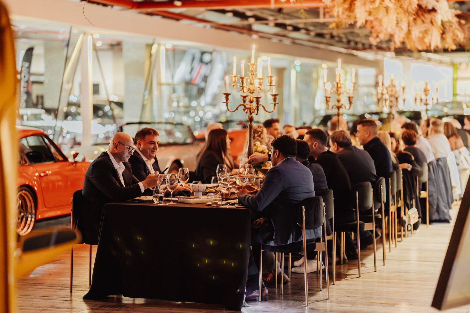 Elegant restaurant interior with dining tables set up along large windows overlooking water during sunset.