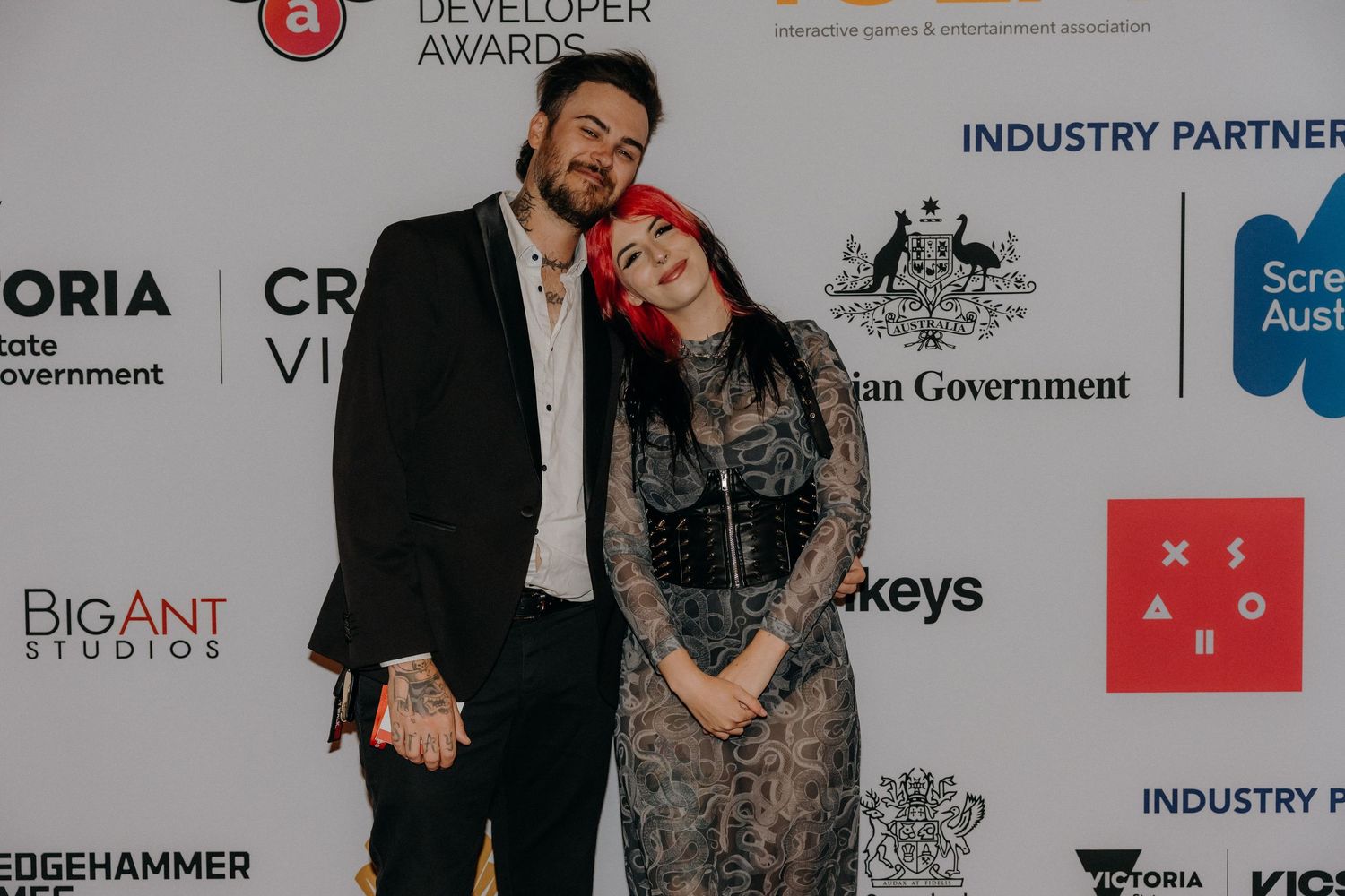 People posing in front of a sponsor wall with company logos at a tech or gaming industry event.