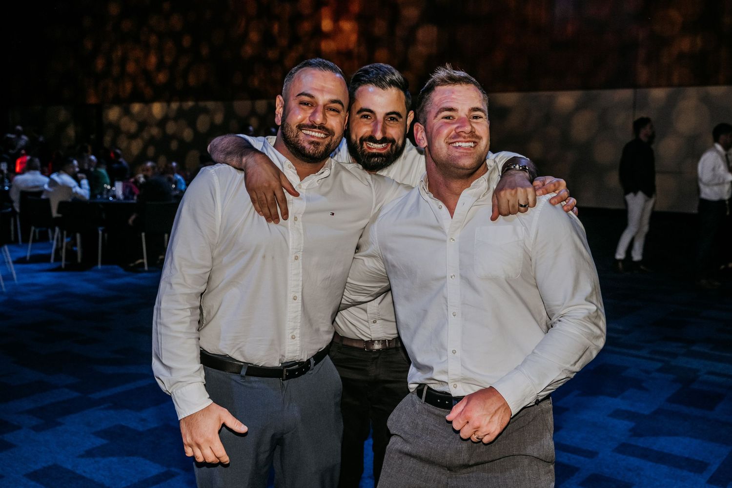 A group of people in white and gray attire posing together at a formal event.