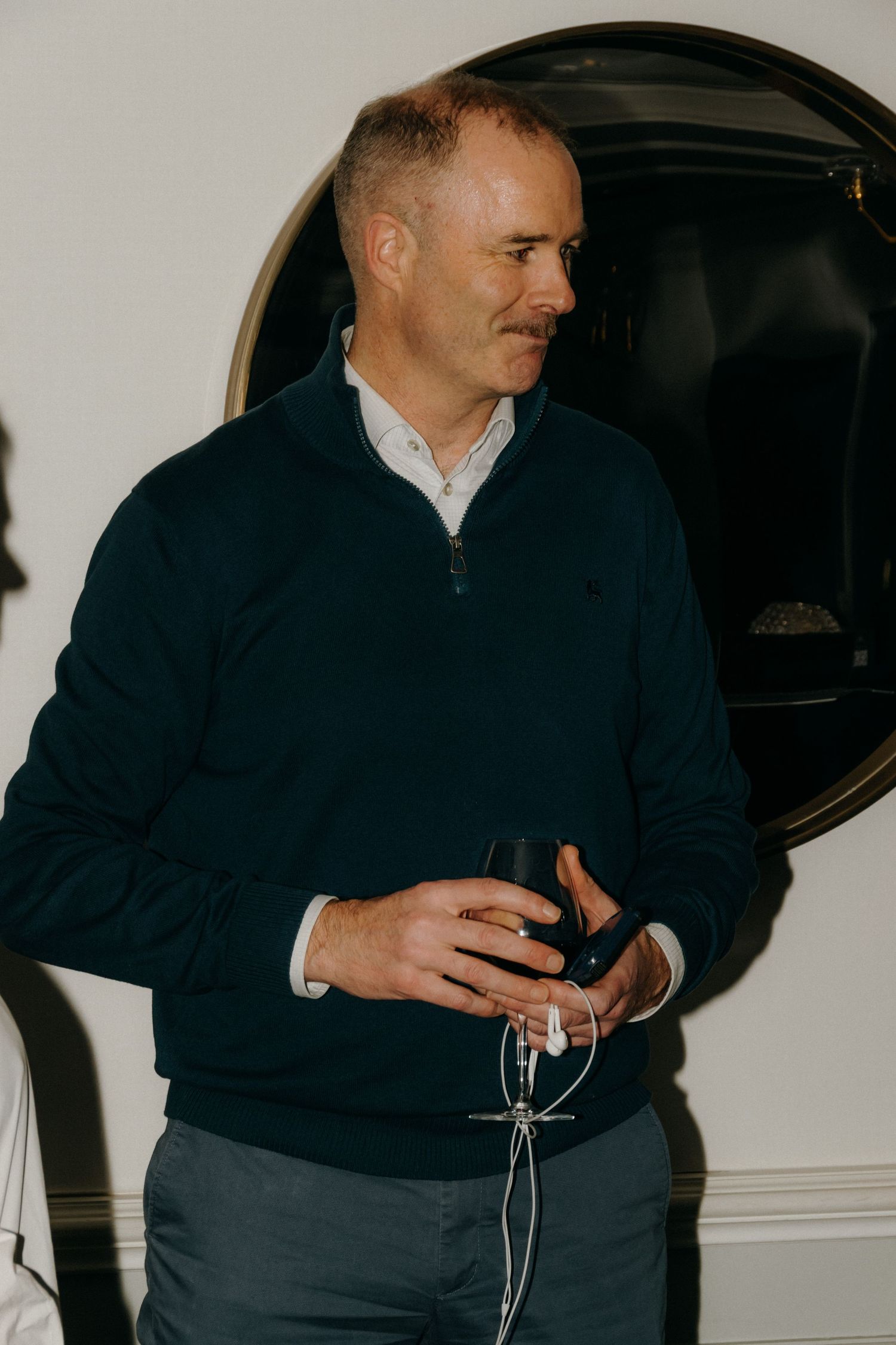 Person in navy jacket shown in sequence holding and examining a dark object against white wall background.