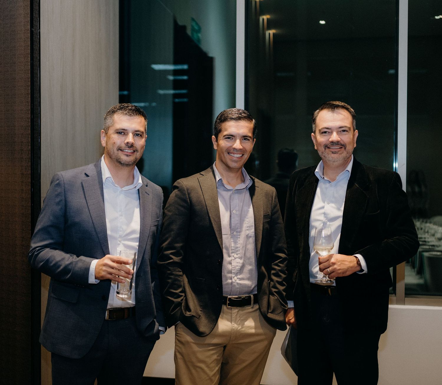 Business professionals engaging in conversation while holding drinks at a networking reception.