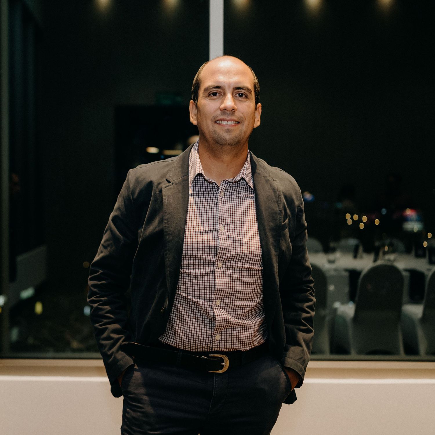 Professional headshot of person in business attire against dark background with ambient lighting.